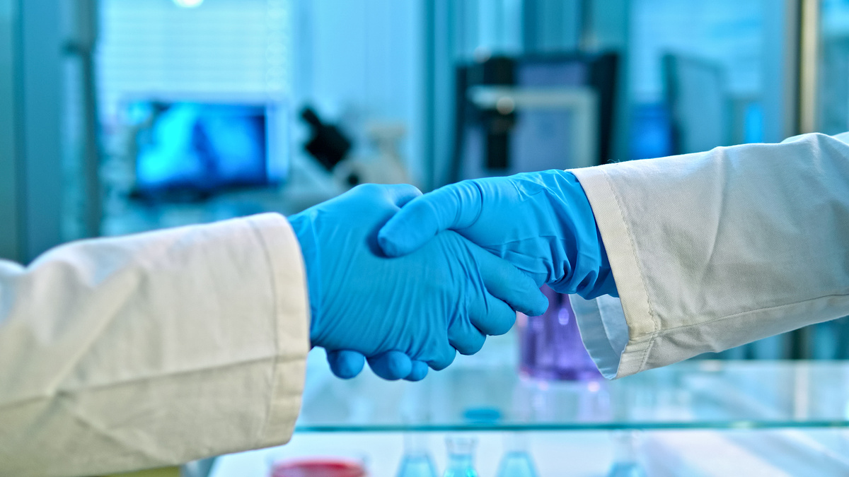 身穿白大褂的科学家在研究实验室里握手