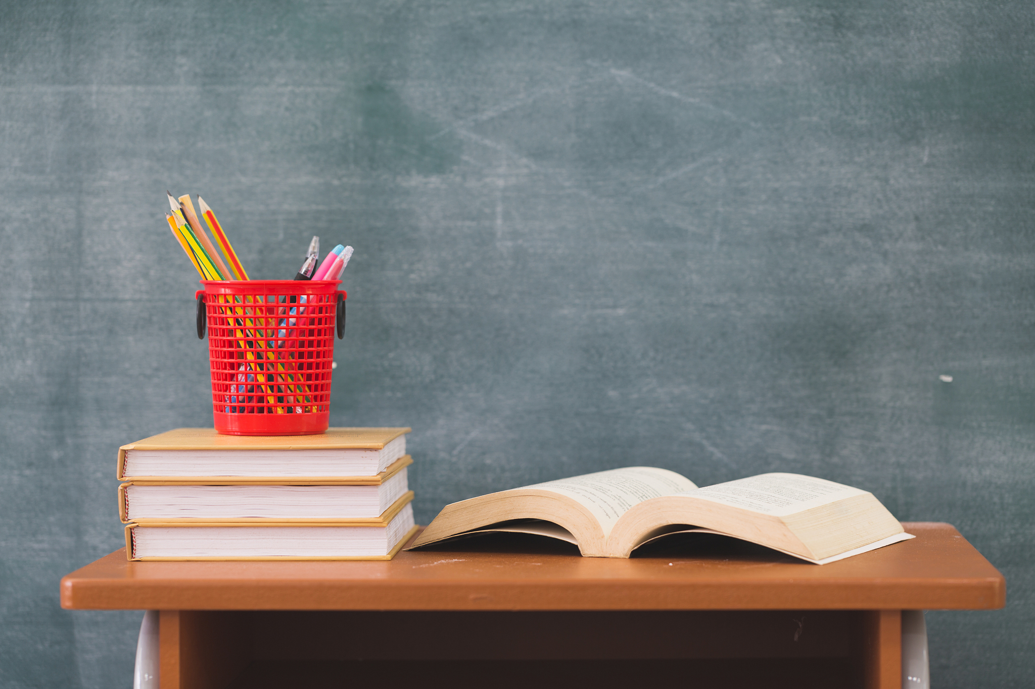 school books on desk, back to school supplies. books and blackbo