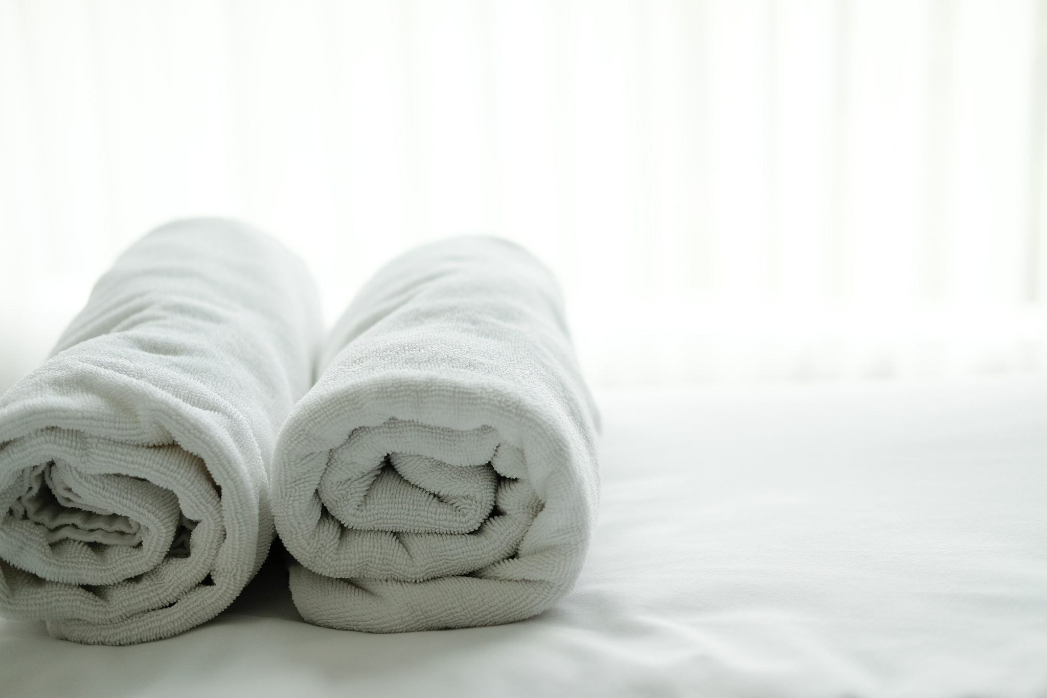 white towel on bed with see through curtain background.