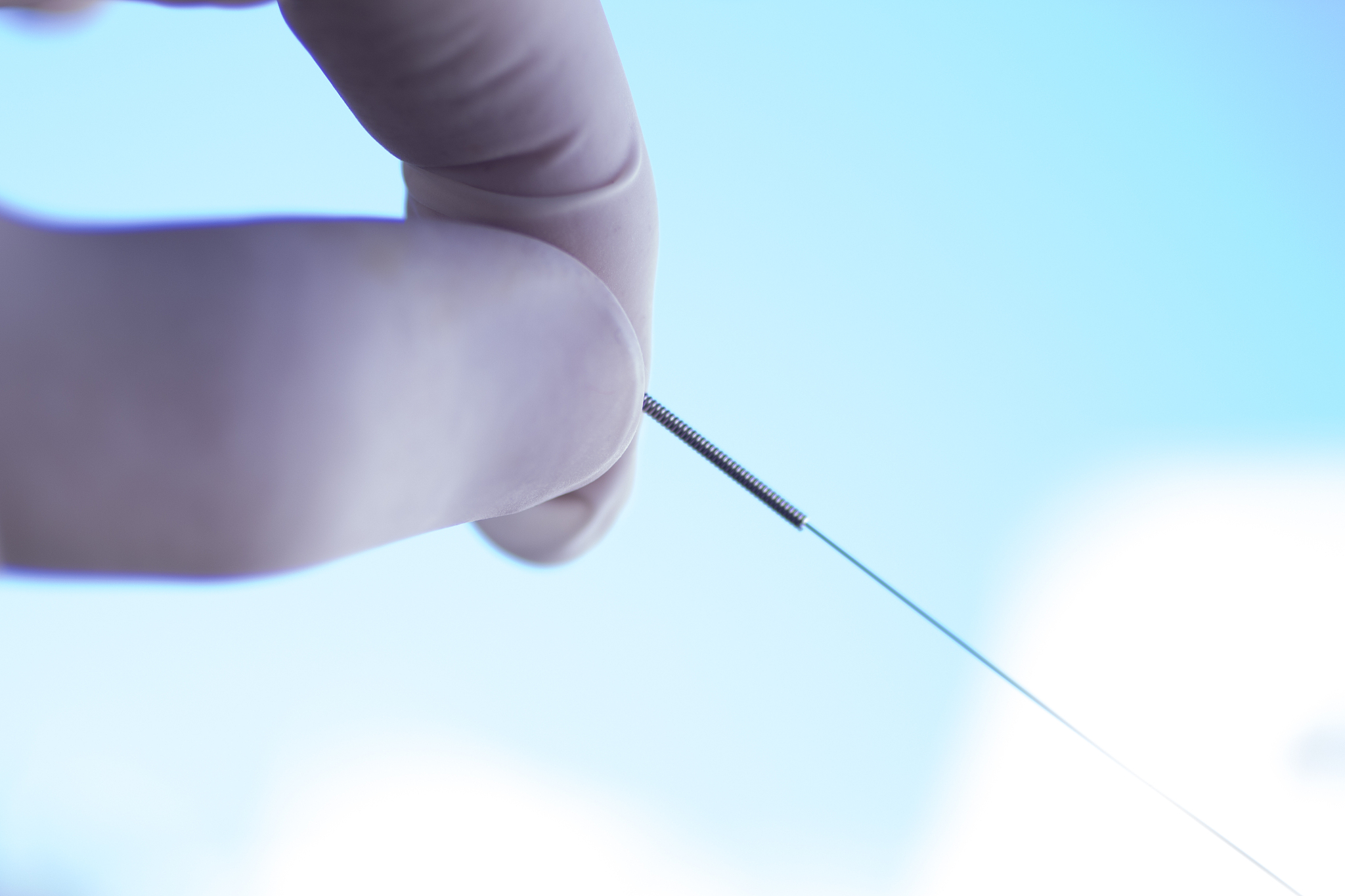cropped hand holding acupuncture needle in hospital