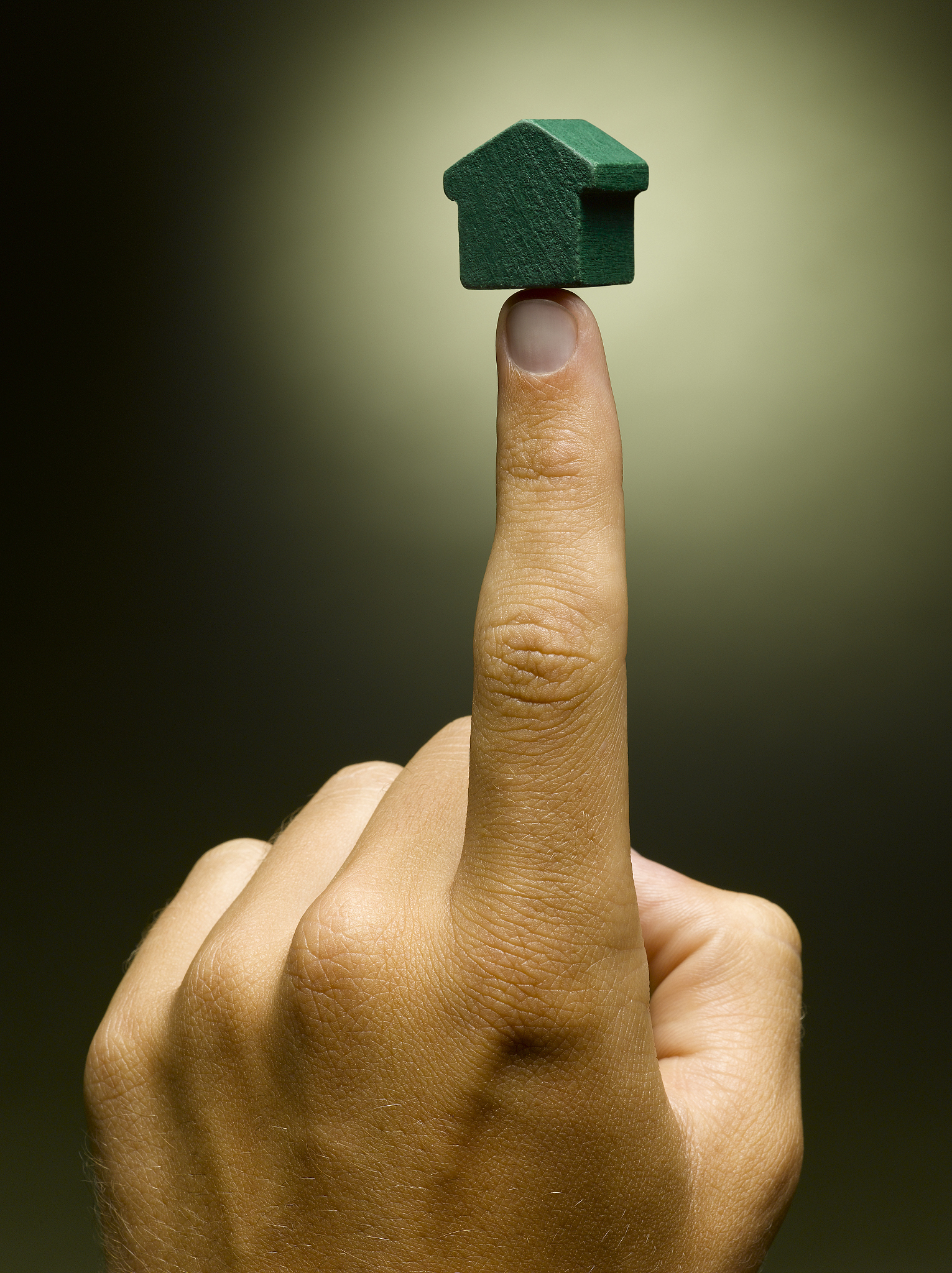 man balancing model house on index finger, close-up
