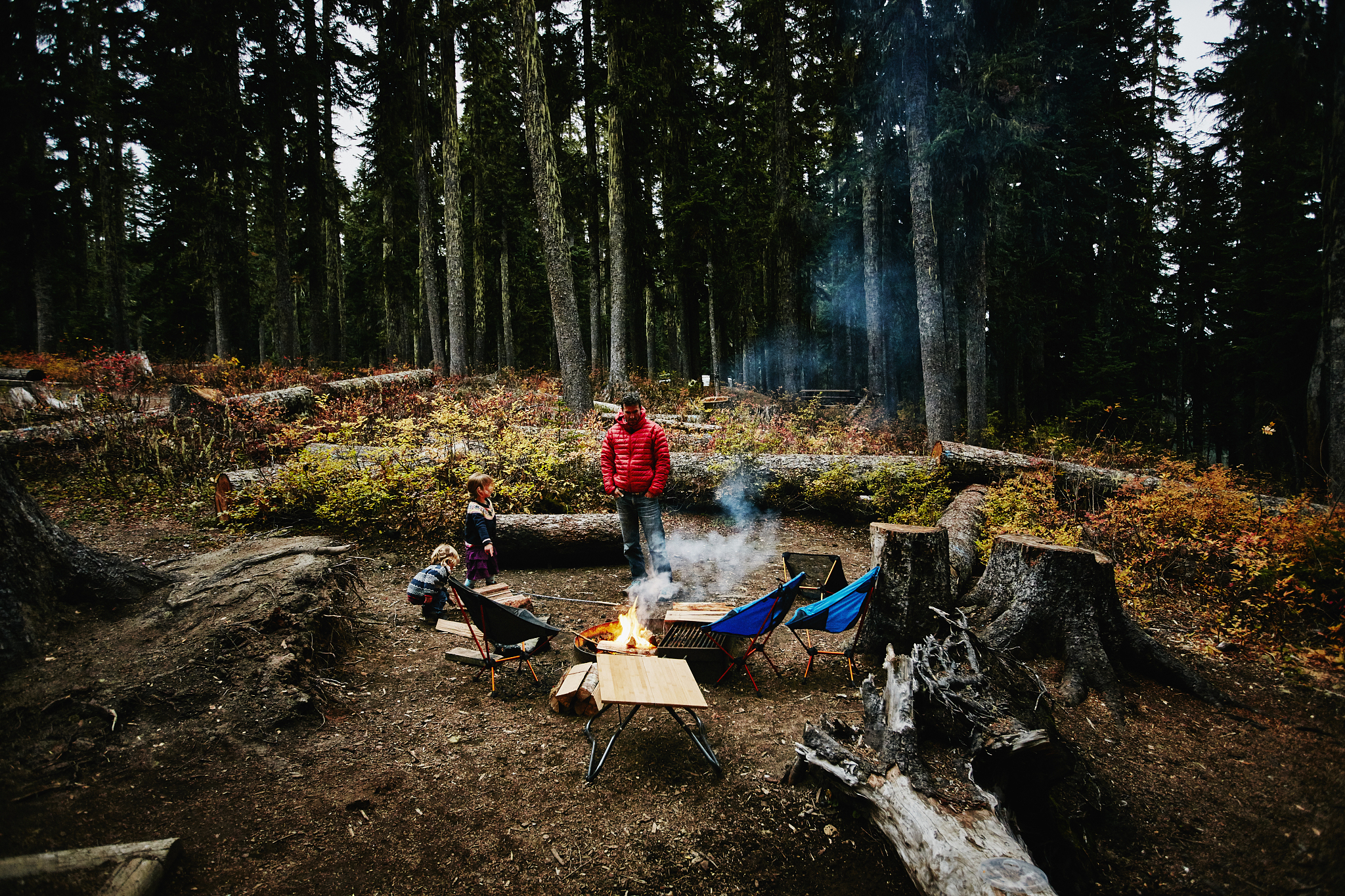 family watching campfire in fire pit at campsite