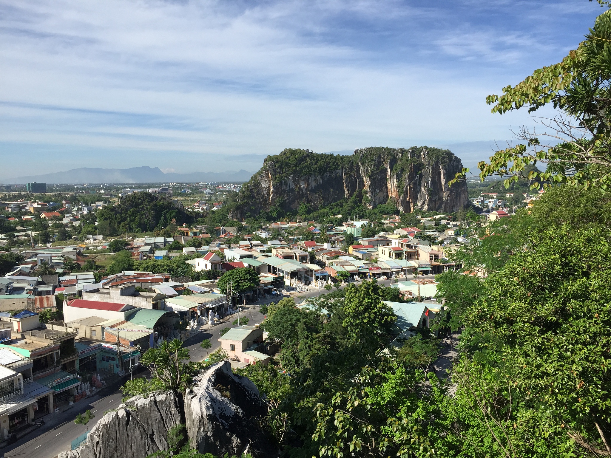 a city in the mountains of tropical laos with a large rock in th
