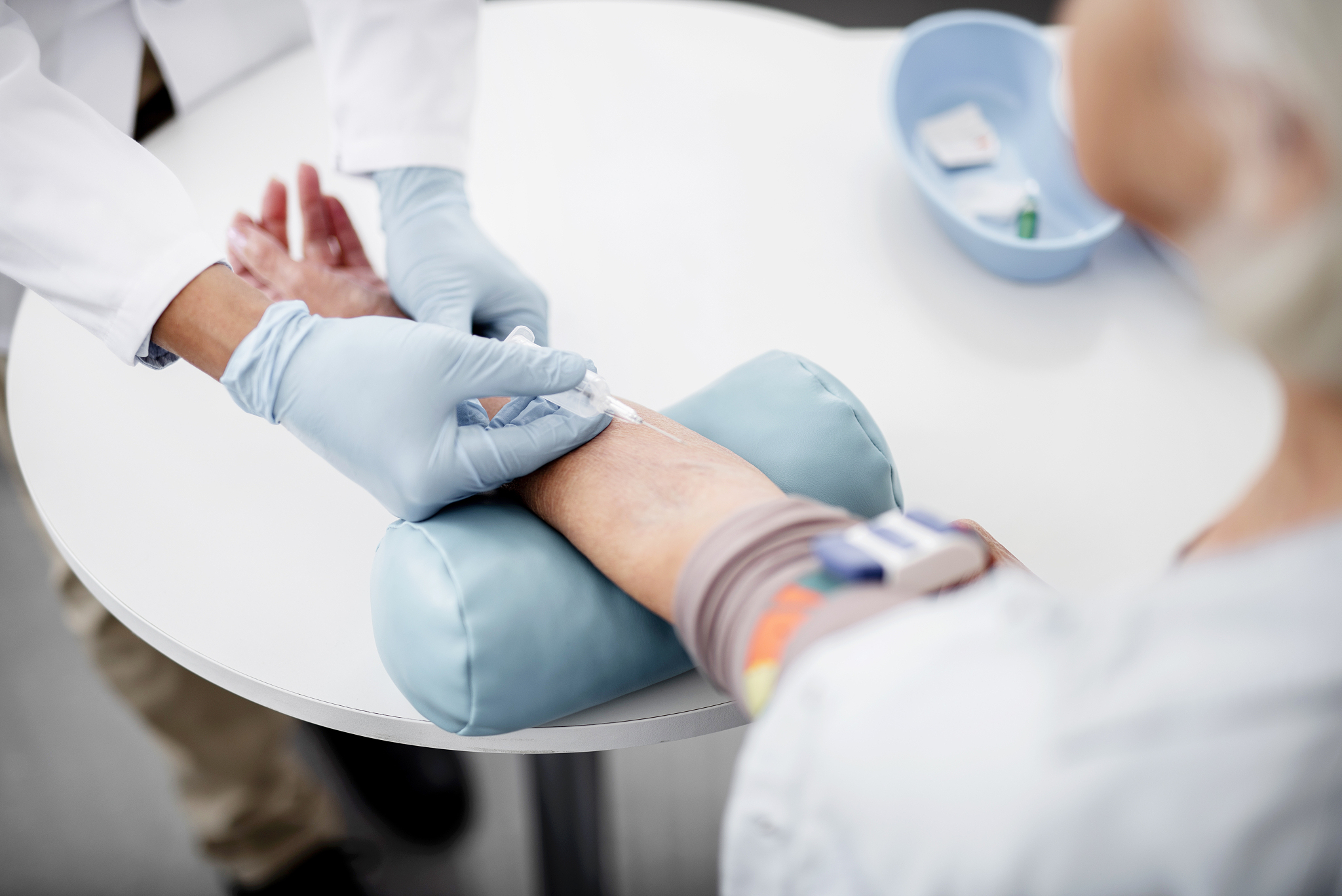 close up of needle in the arm of patient and hands of doctor hol