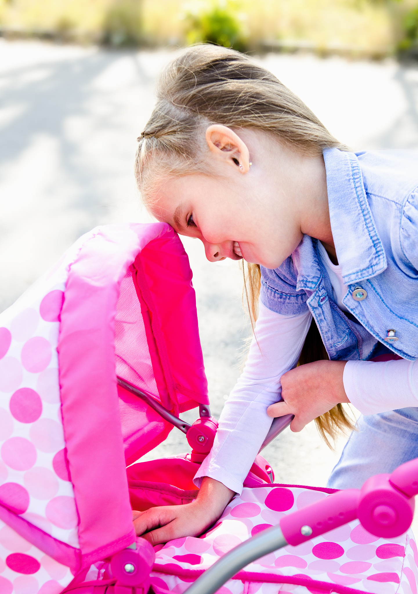 cute smiling little girl playing with her toy carriage