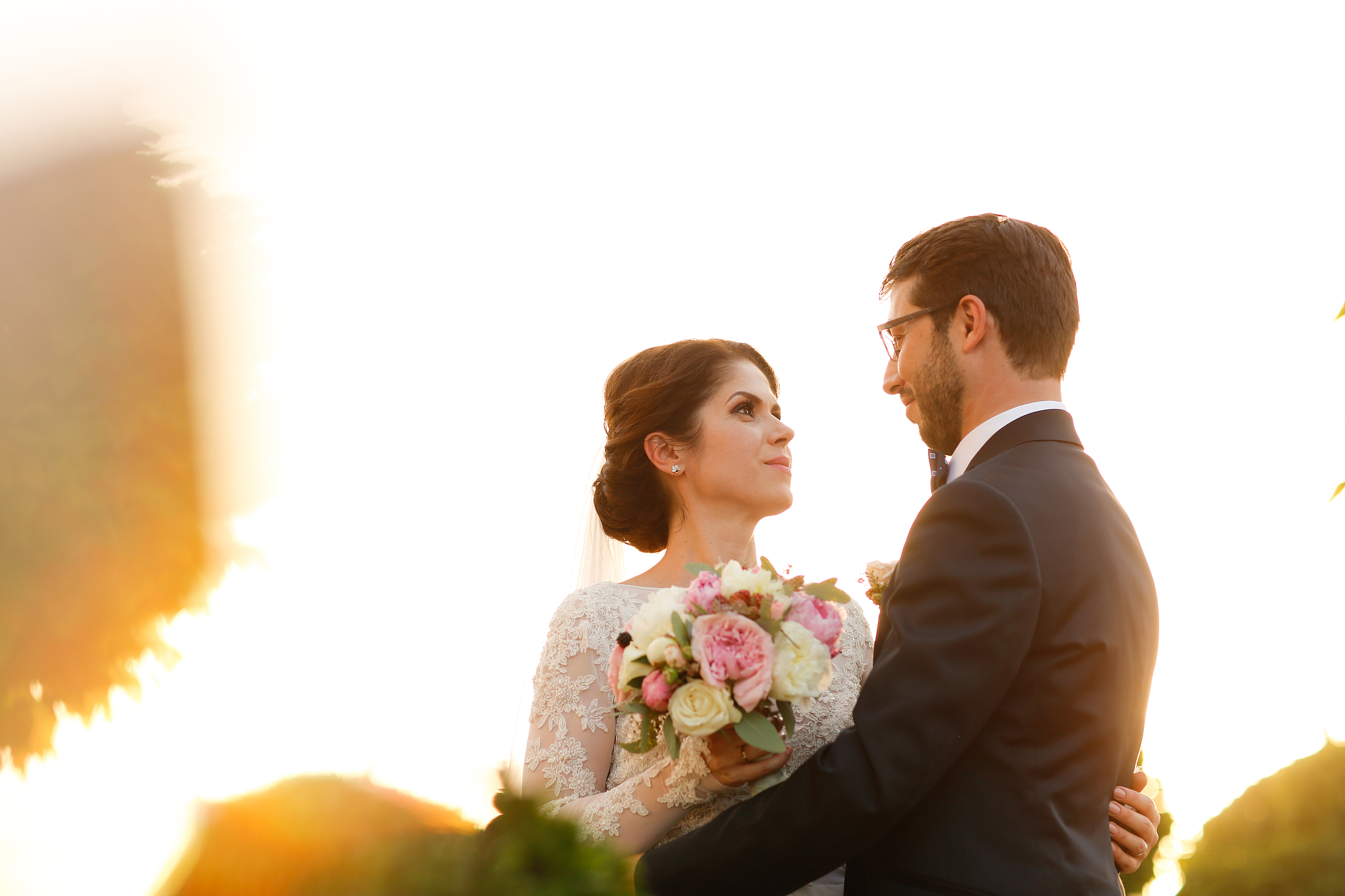 joyful bride and groom with bouquet embracing outdoors