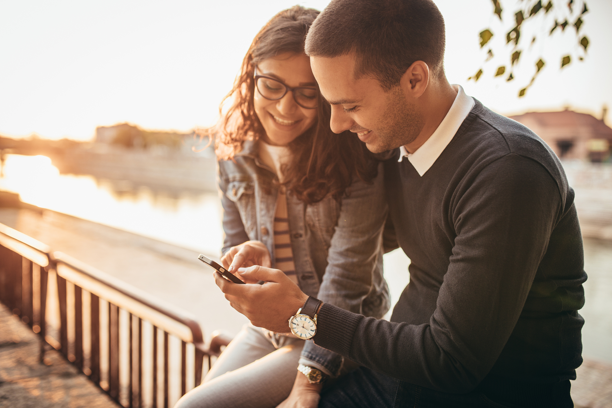 happy young couple walking at the street and using phone