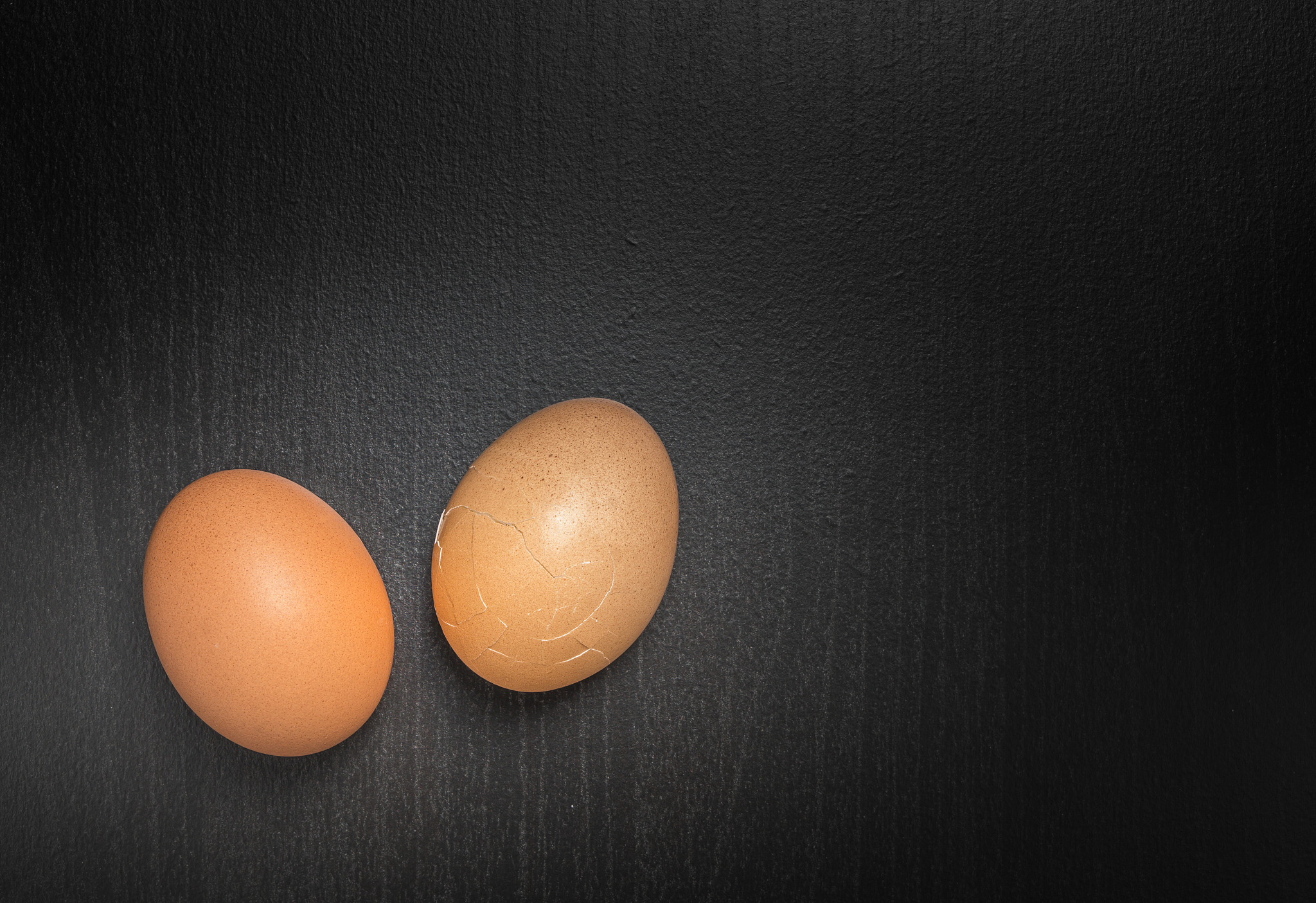 two cracking egg on black background with copy space