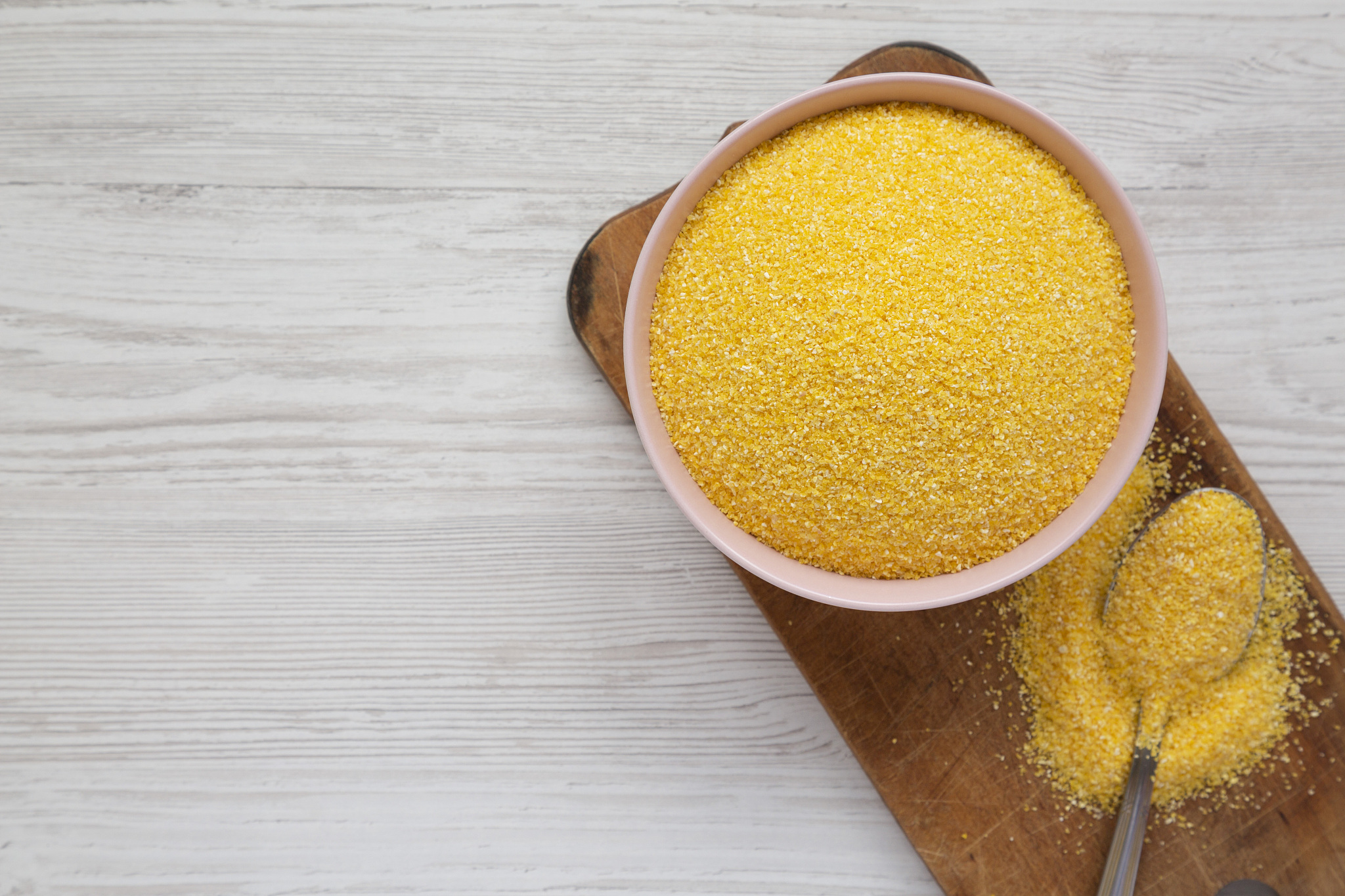 dry organic masarepa corn meal in a pink bowl over white wooden 