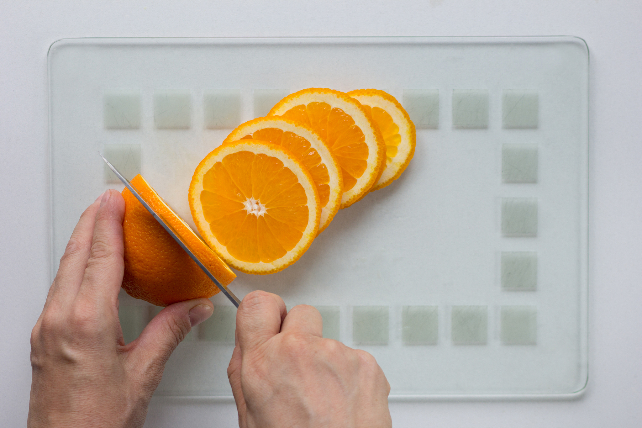 woman hand cut orange with knife on white background