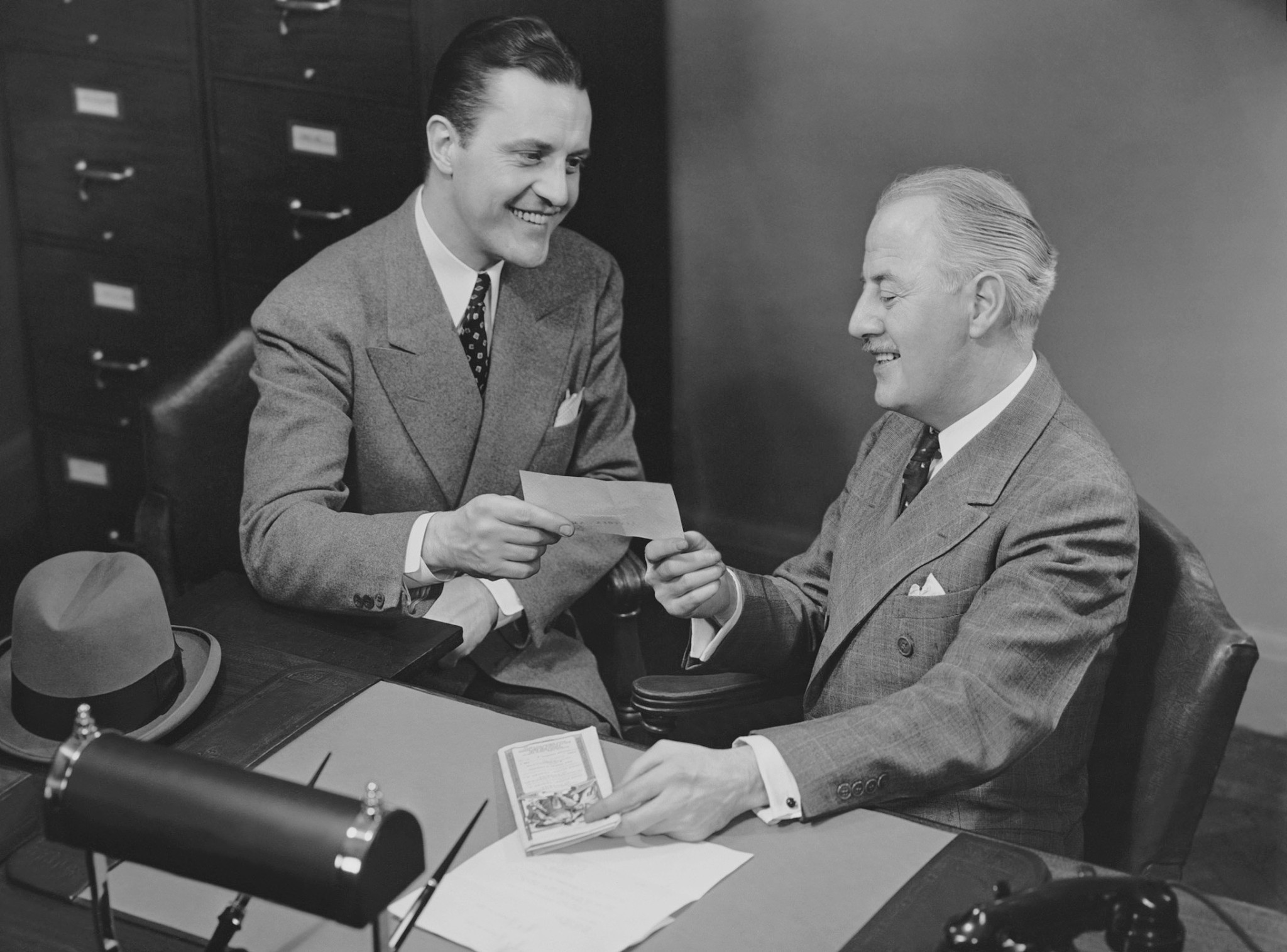 men sitting at desk discussing insurance papers