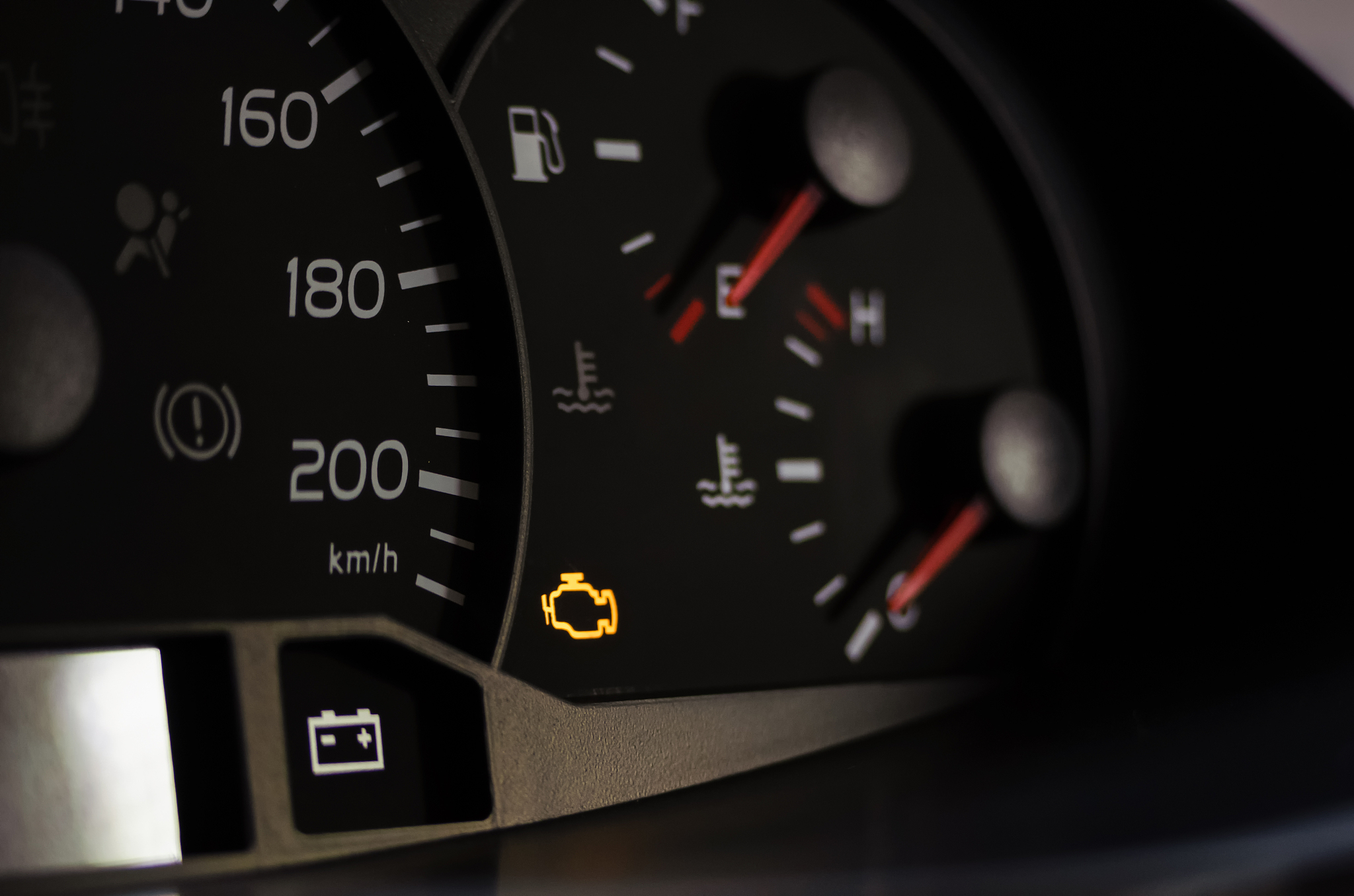 yellow lit engine error sign on car dashboard close up