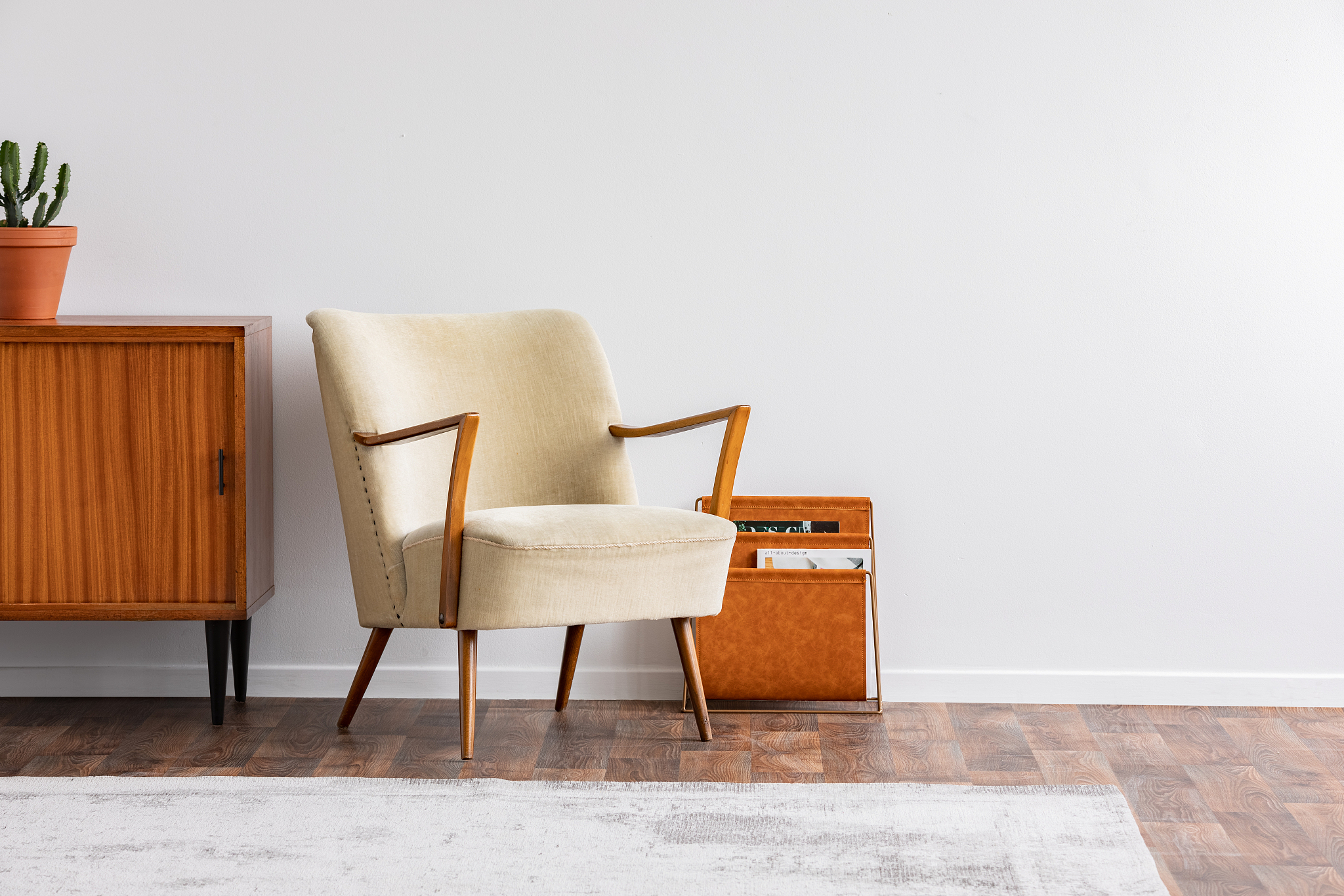 armchair next to wooden cabinet with plant in vintage grey flat 