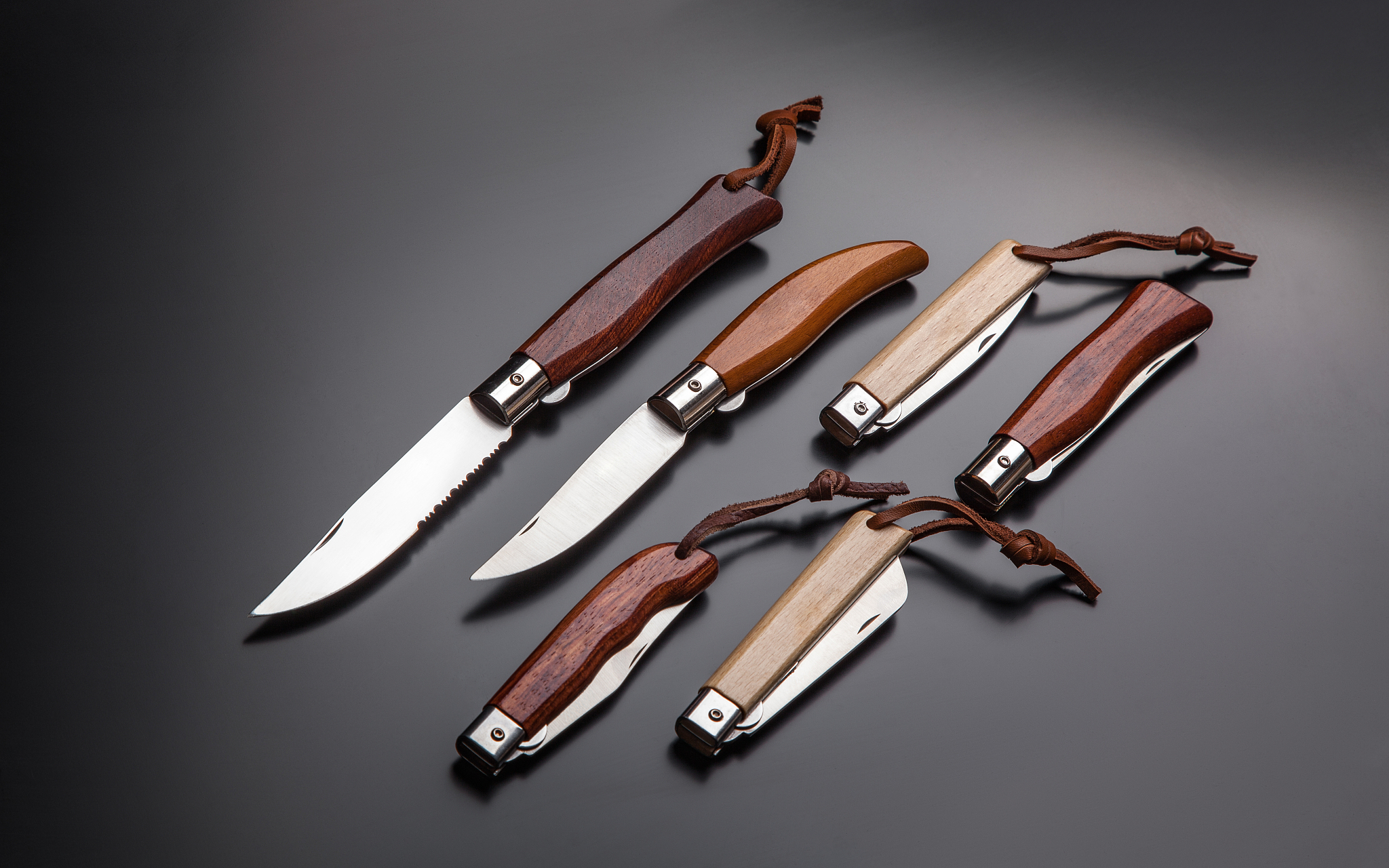 folding pen knives with wooden handles on a gradient gray-black 