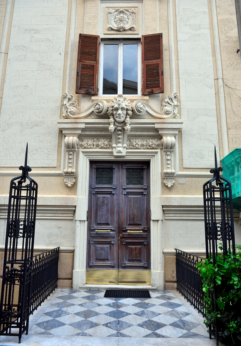 用一段话描写一栋黄色的瓦顶、黑色的柱子和褐色的墙壁。正面还有一扇气派的红色大门的洋馆豪宅