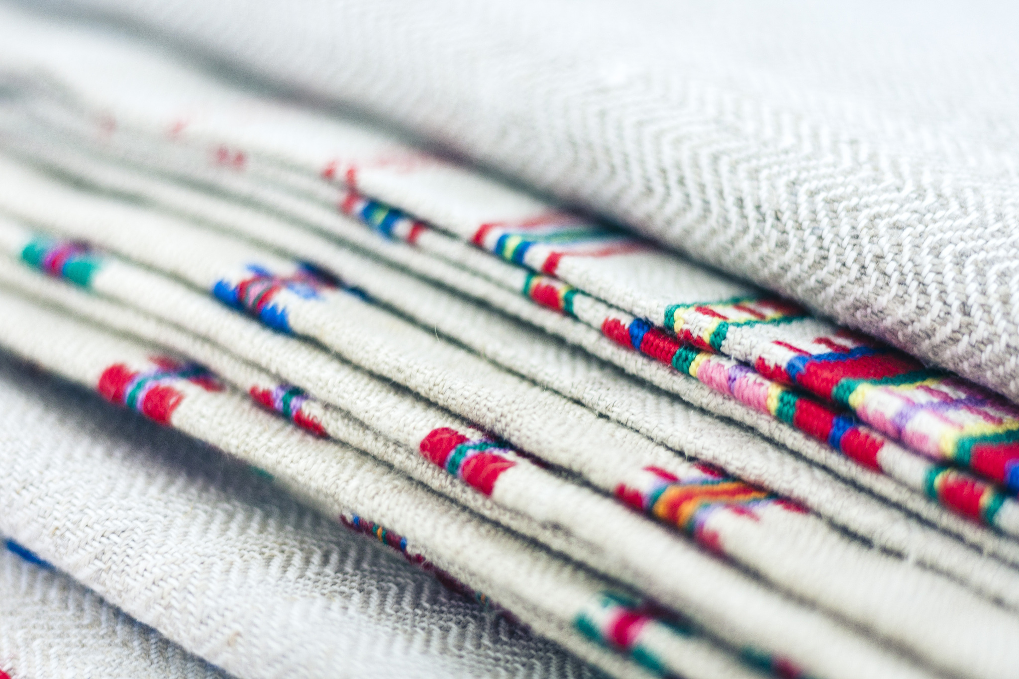 a stack of woven linen towels with embroidery, traditional handm