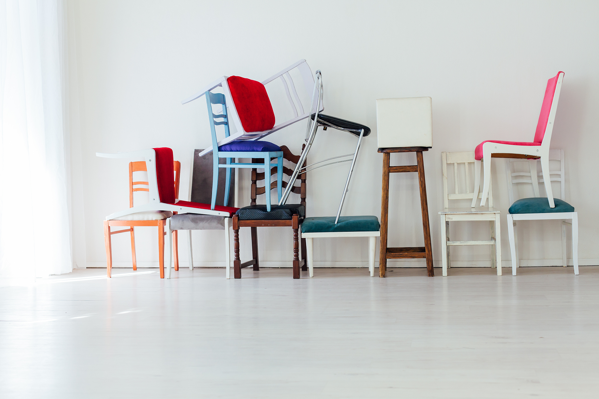 many multicolored chairs stand in the white room