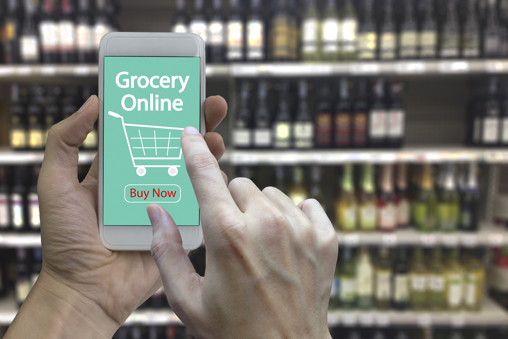 hand use smartphone with grocery online on screen over blurred s