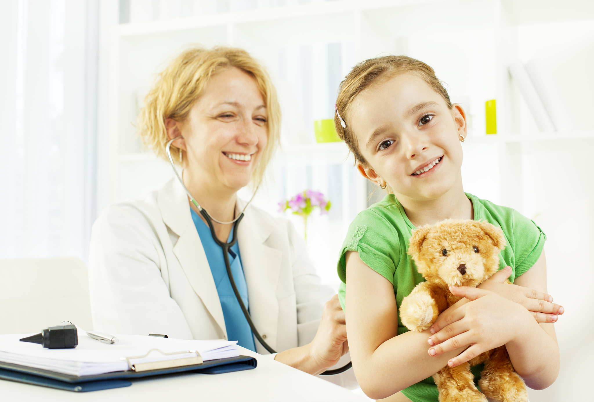 child with teddy bear at doctors office.