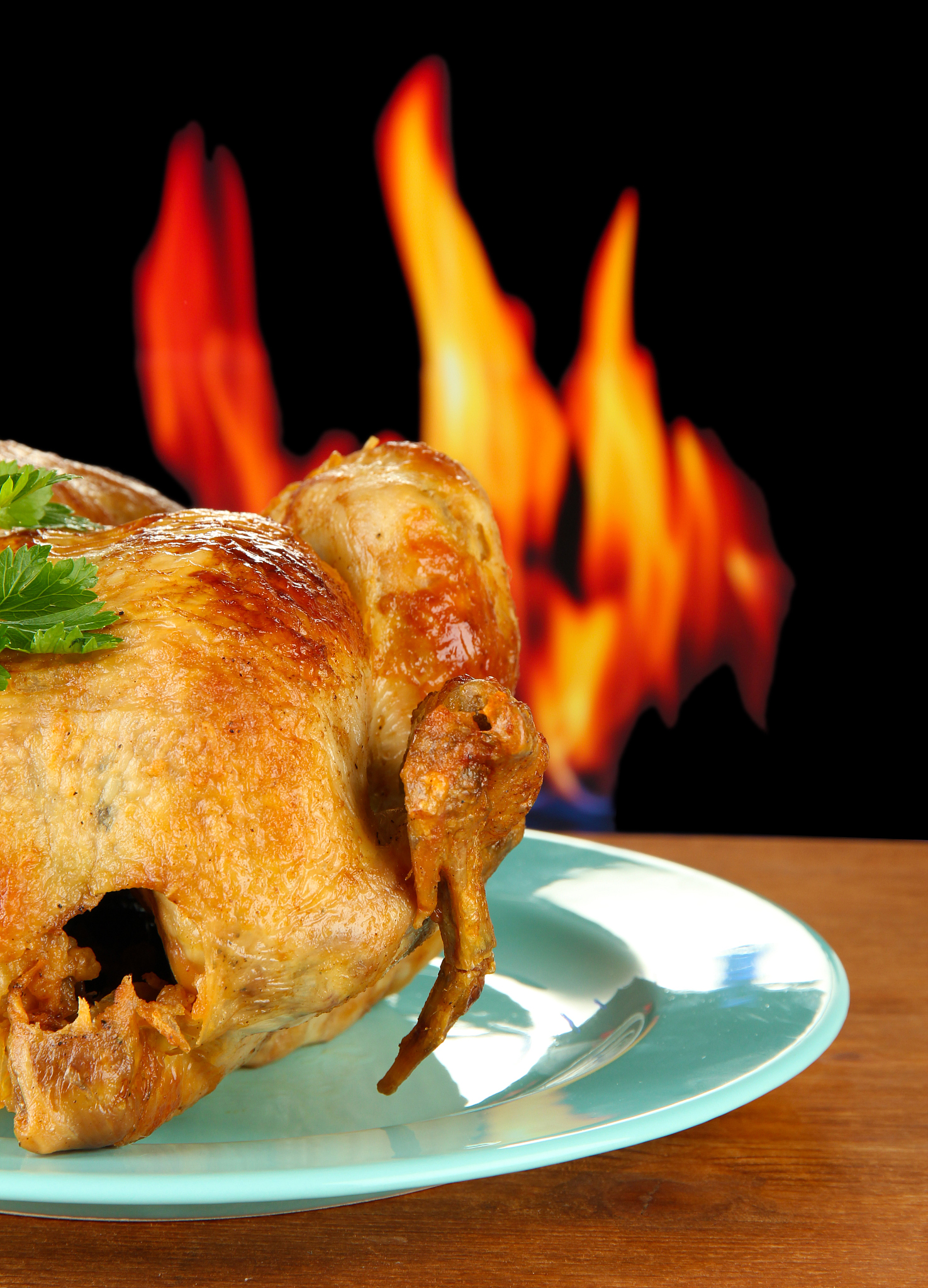 roasted whole chicken on a plate on wooden background close-up