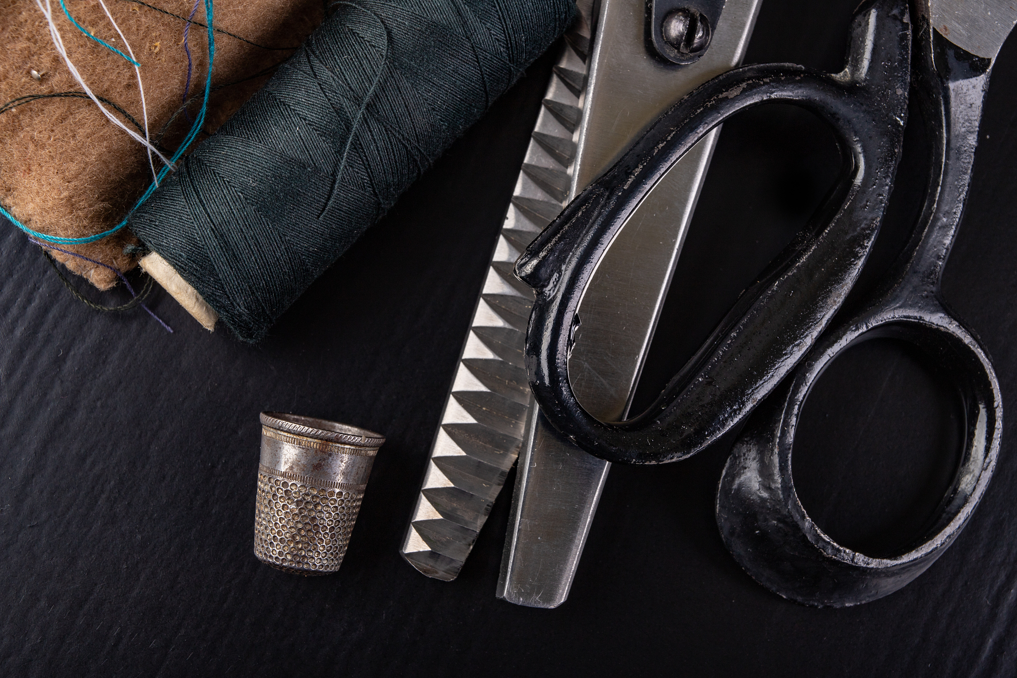 old sewing accessories on the black table. shears, threads and t