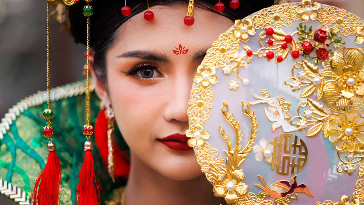 一位身着中国传统服饰的优雅女士,手持一把华丽的金色