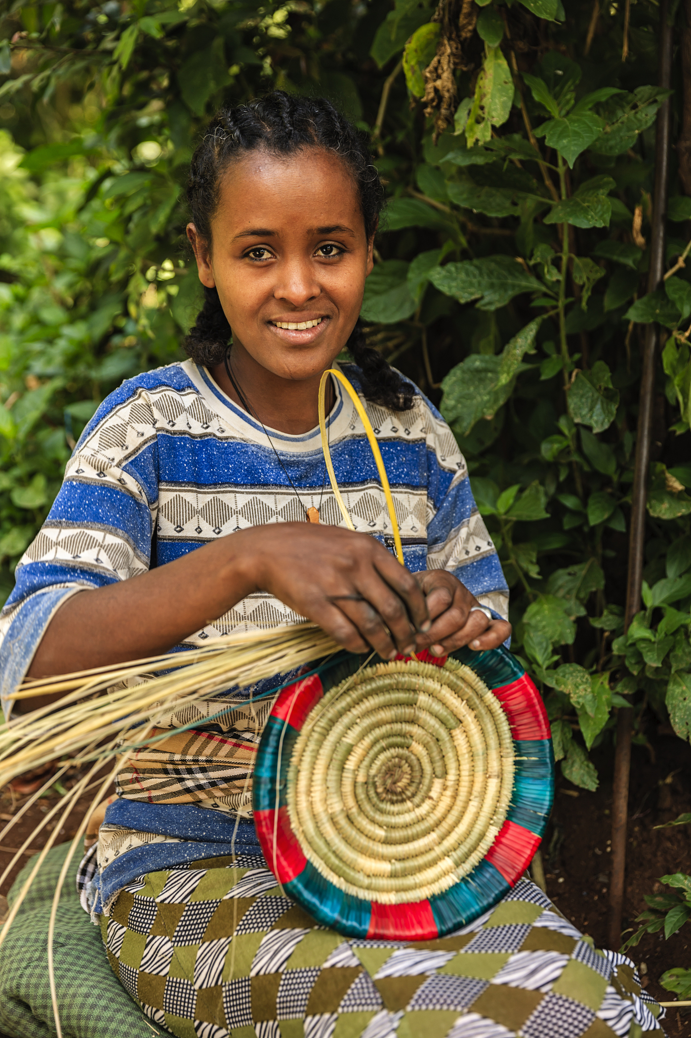 young african woman weaving food basket in ethiopia, east africa