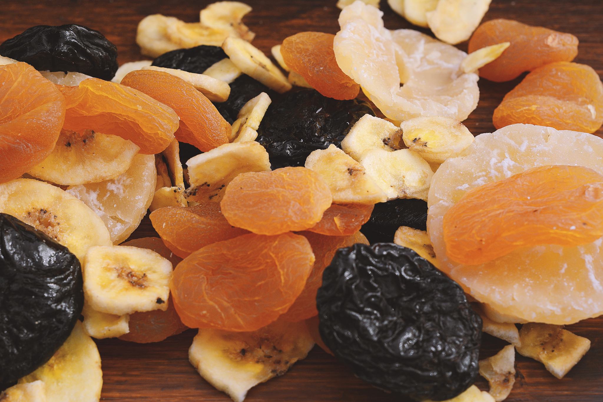 close up of different dried fruits on wooden background