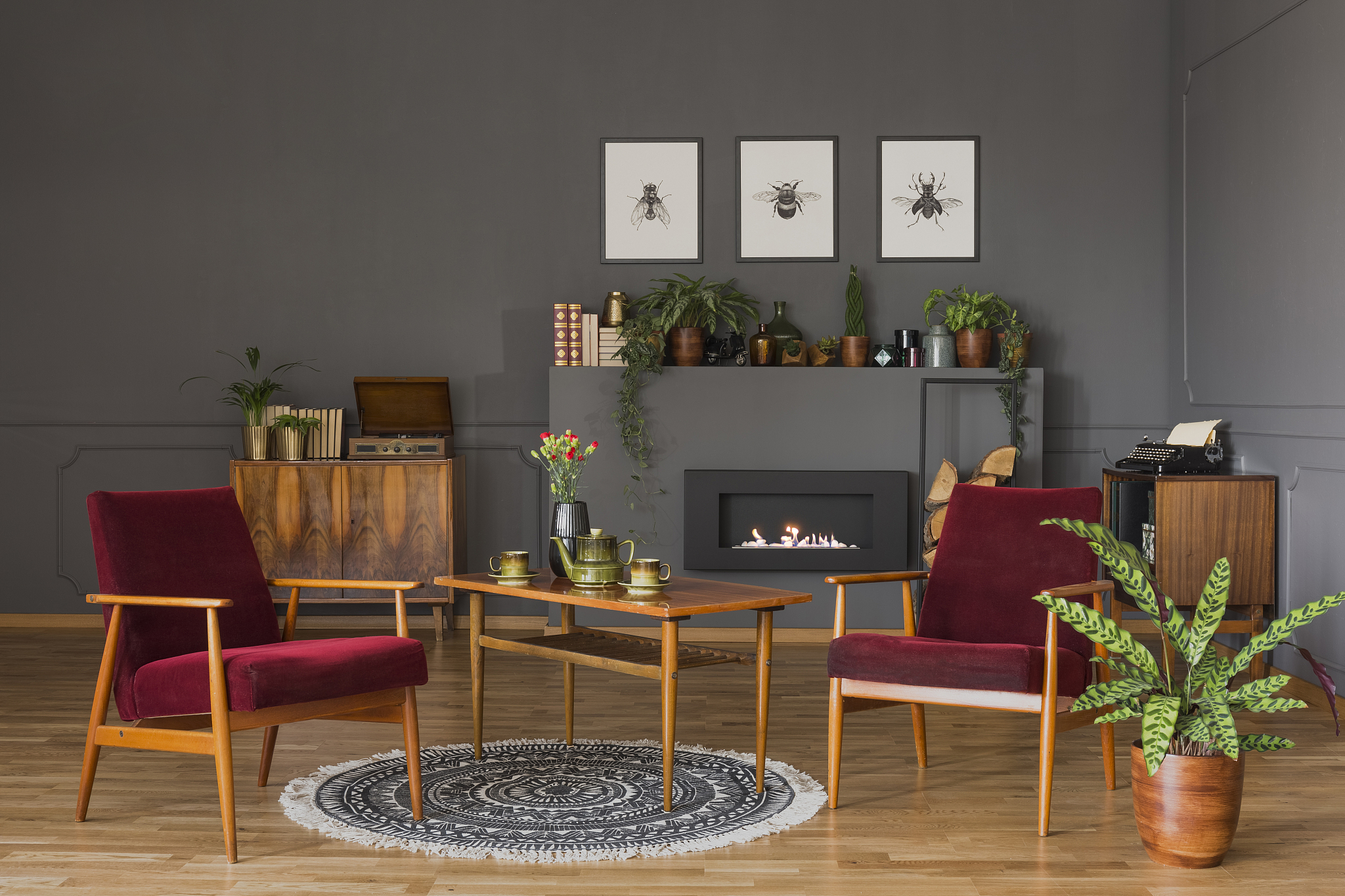 table with flowers between dark red wooden armchairs in living r