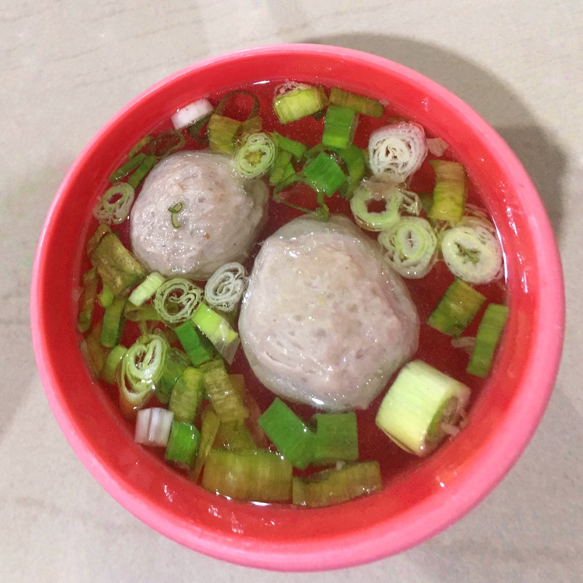 一碗肉丸汤,上面放着洋葱片.
