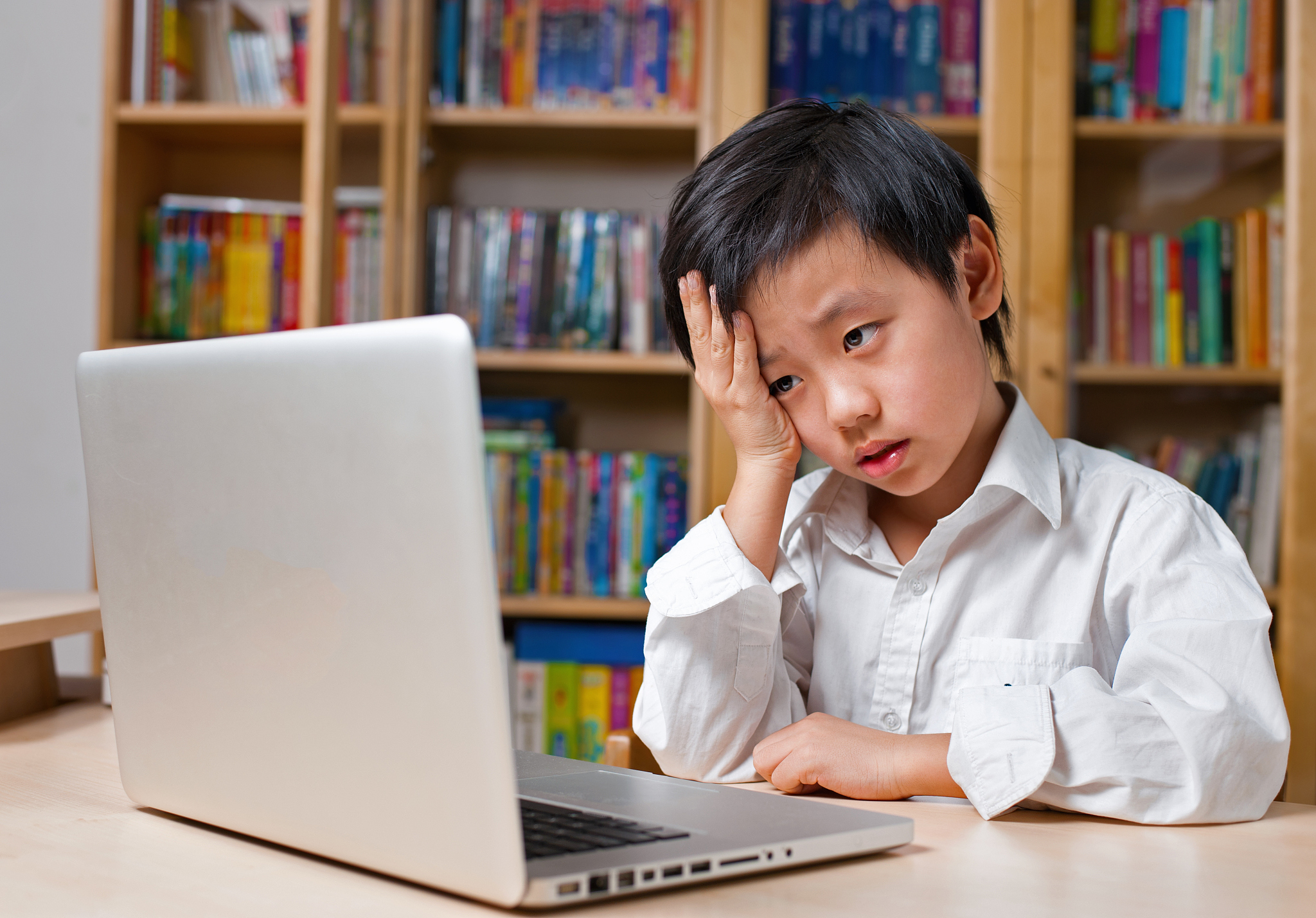 asian boy looking unhappy in front of laptop computer
