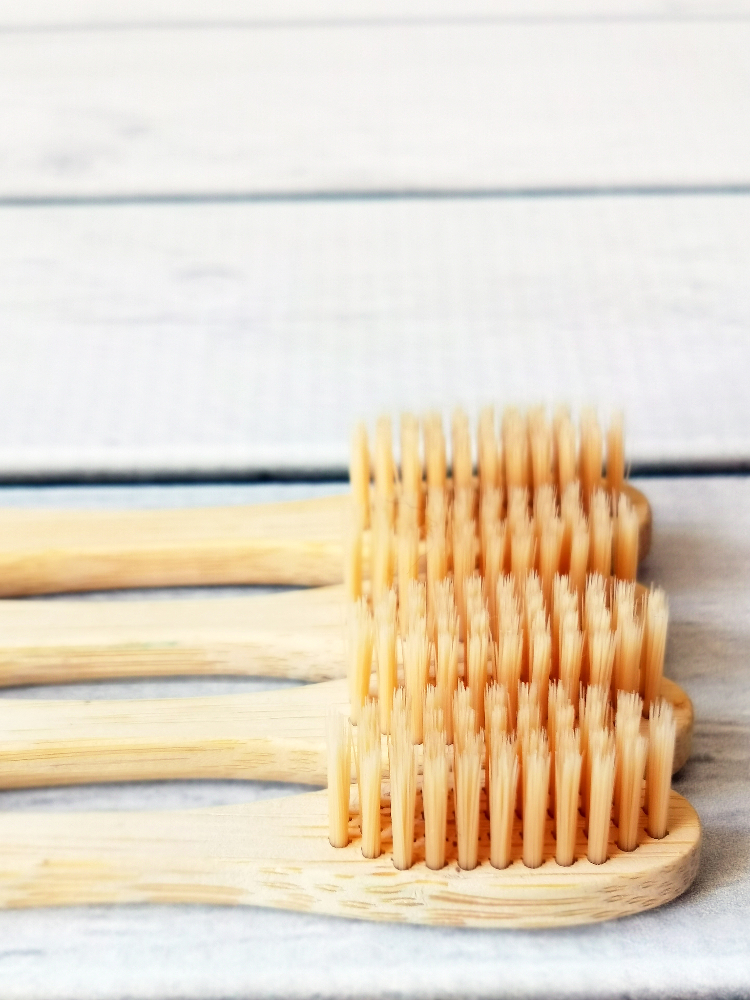 a family set of four wooden toothbrushes on white wooden backgro
