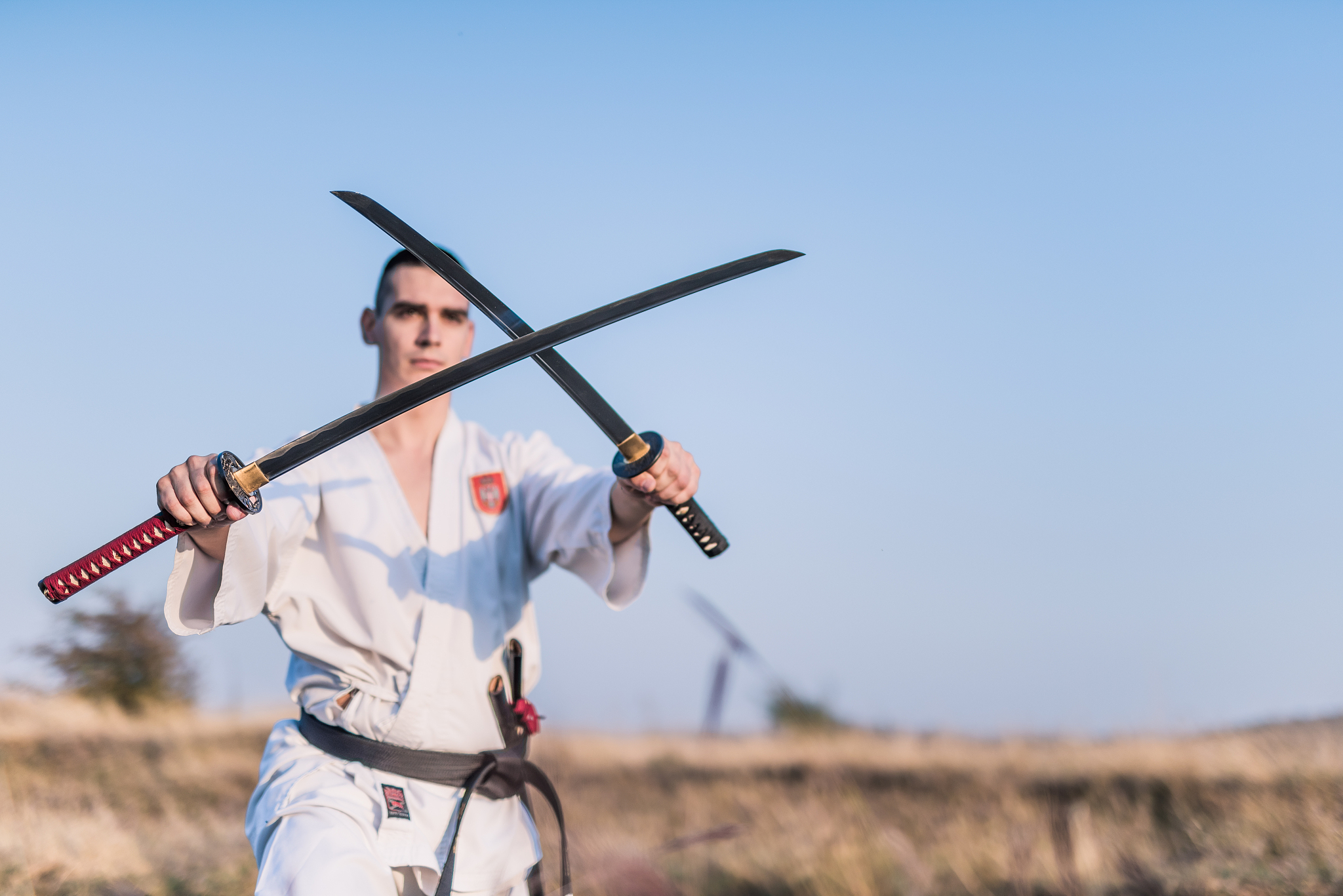 young martial artist holding two katanas together.