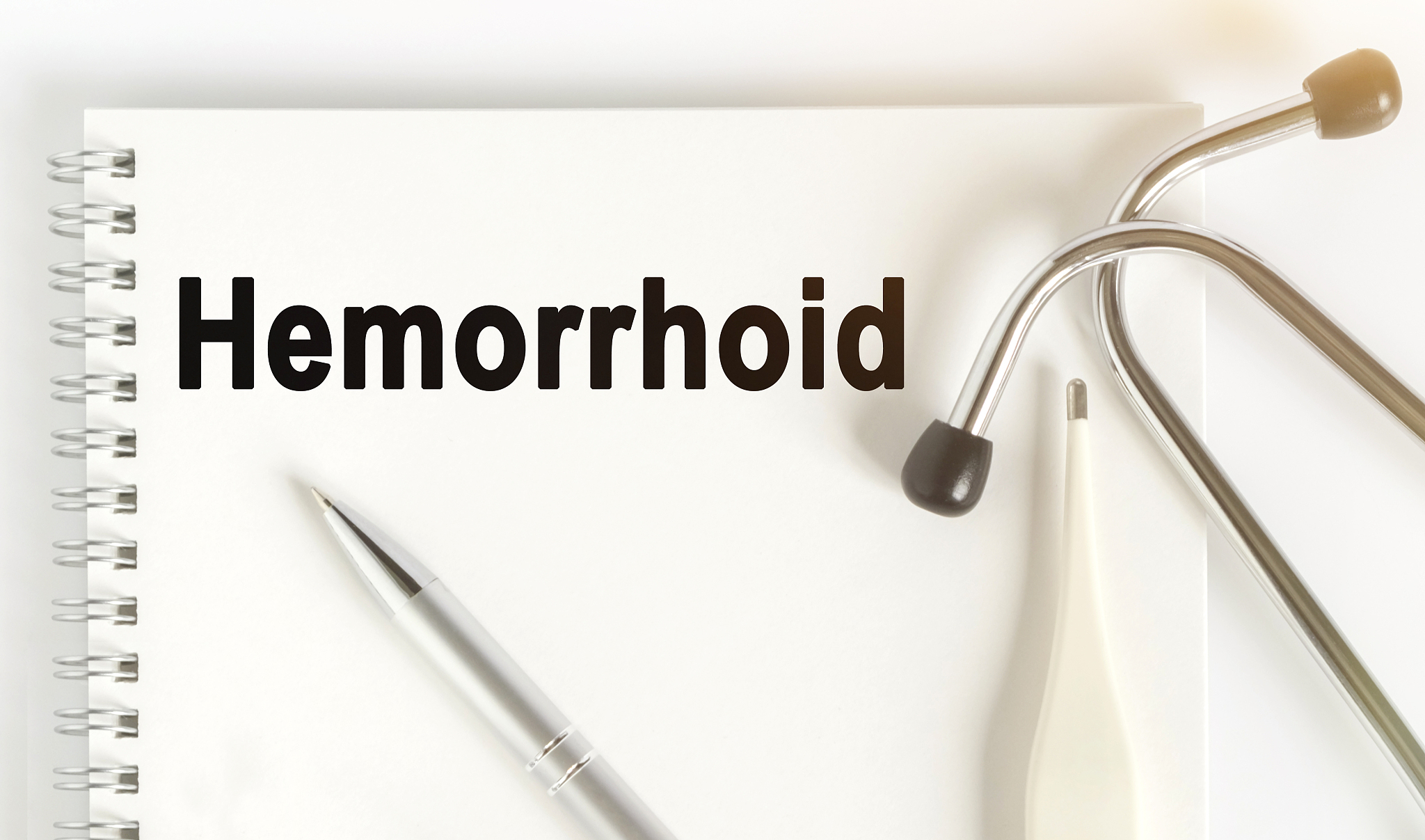 on the table are a stethoscope, a thermometer, a pen and a noteb