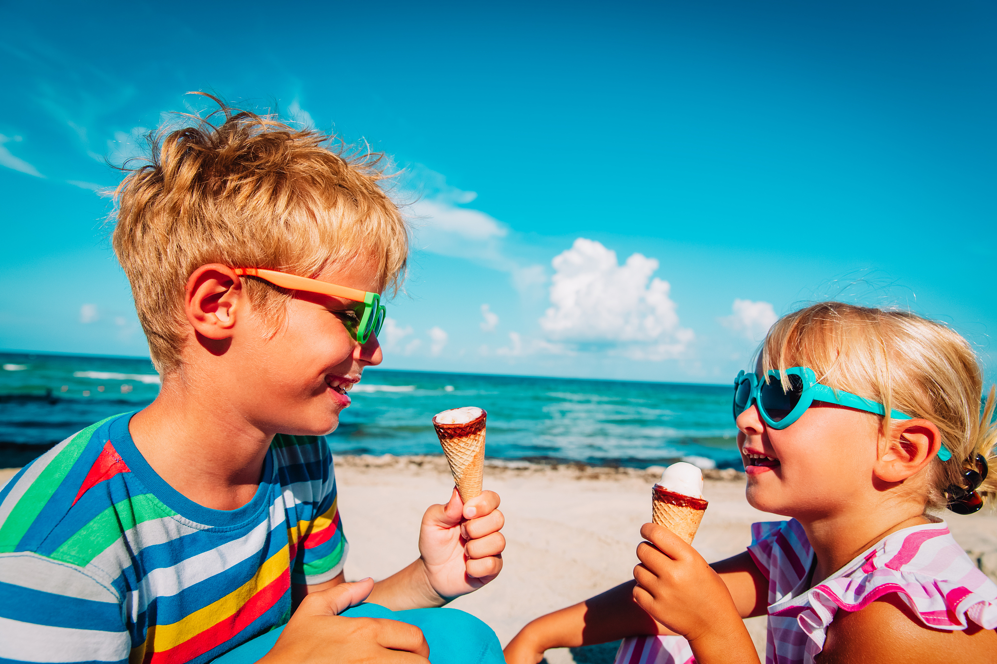 cute boy and girl eating ice cream on beach