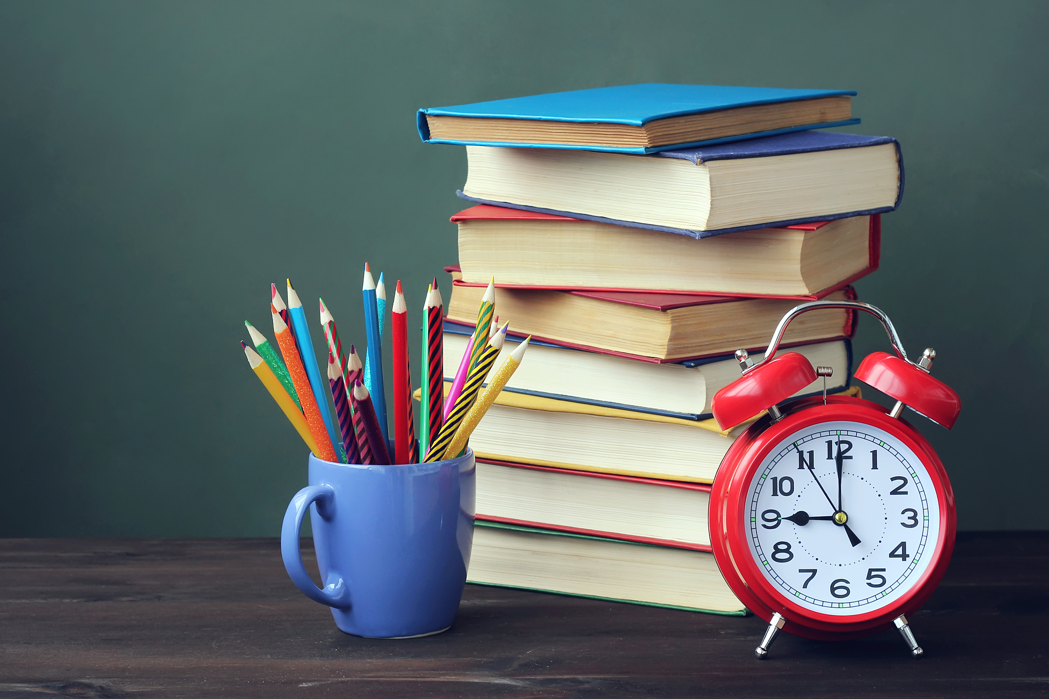 stack of books, pencils and alarm clock on the table.