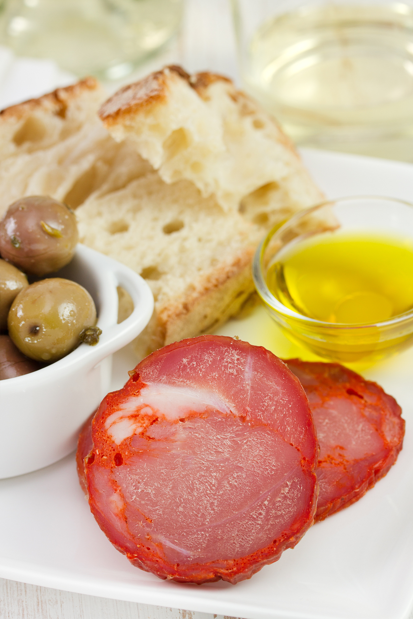 cut sausage with olives, olive oil and bread