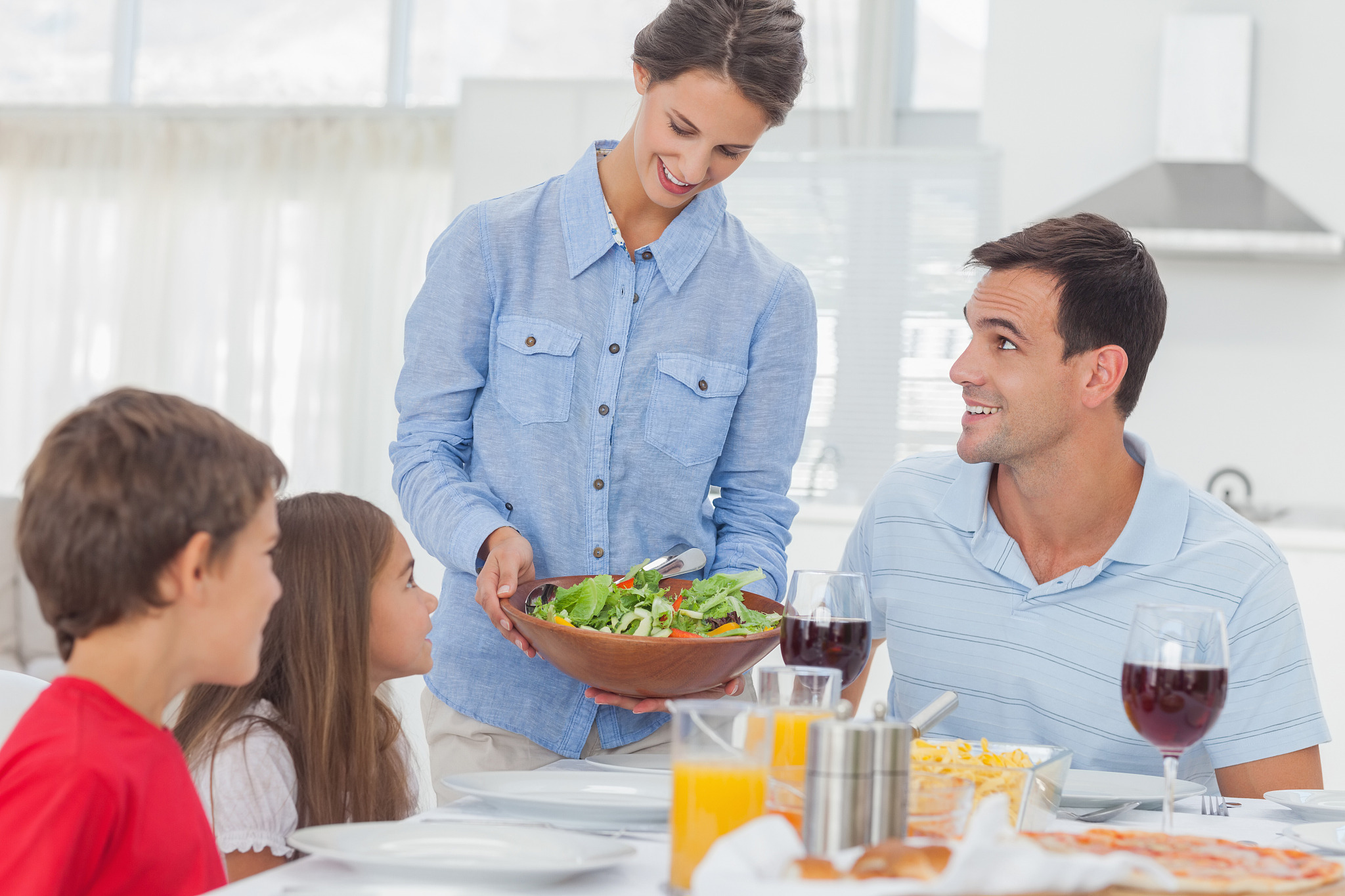 pretty woman bringing a salad to her family for the dinner