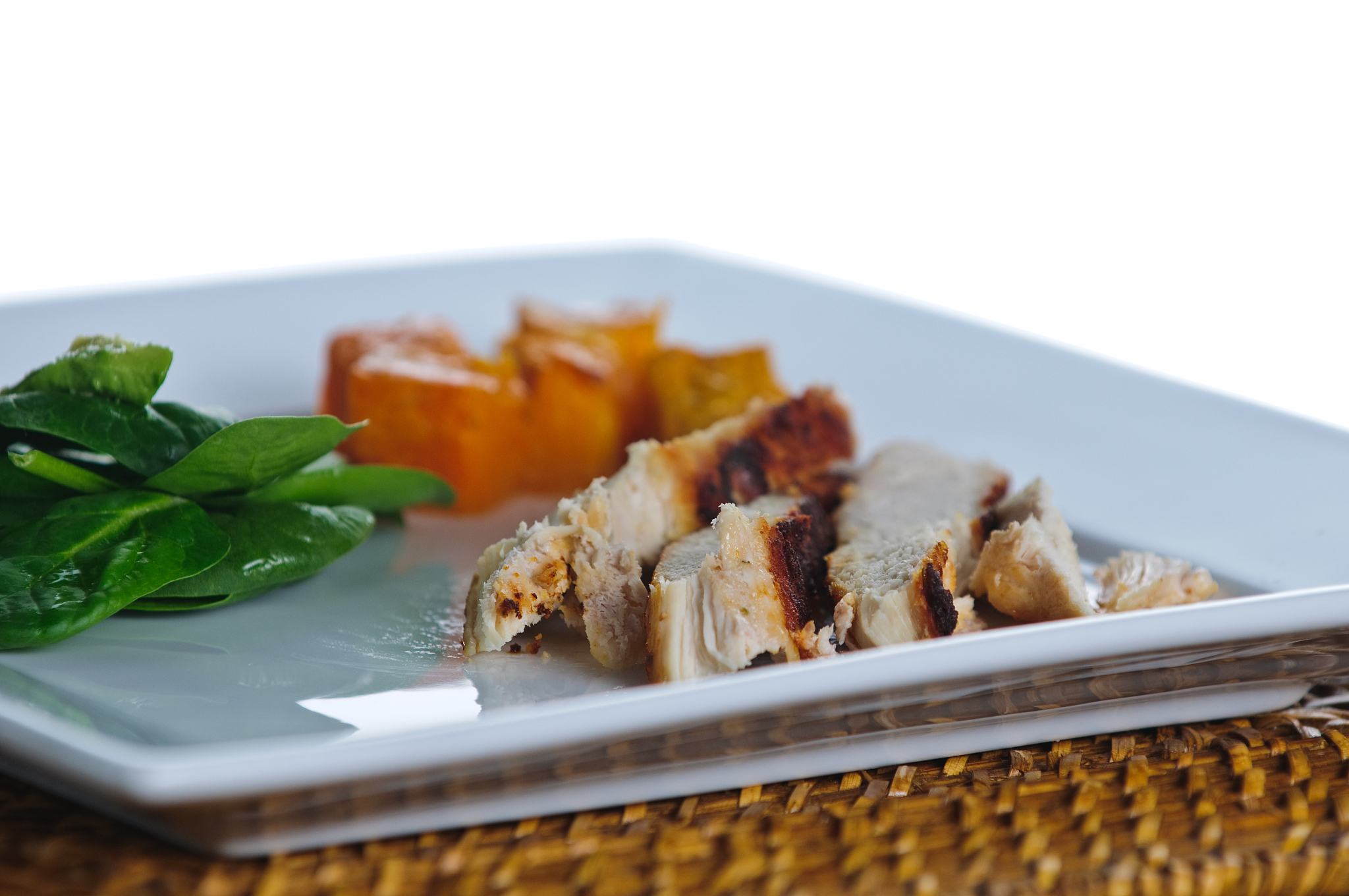 plate of chicken, spinach salad with avocado and baked squash