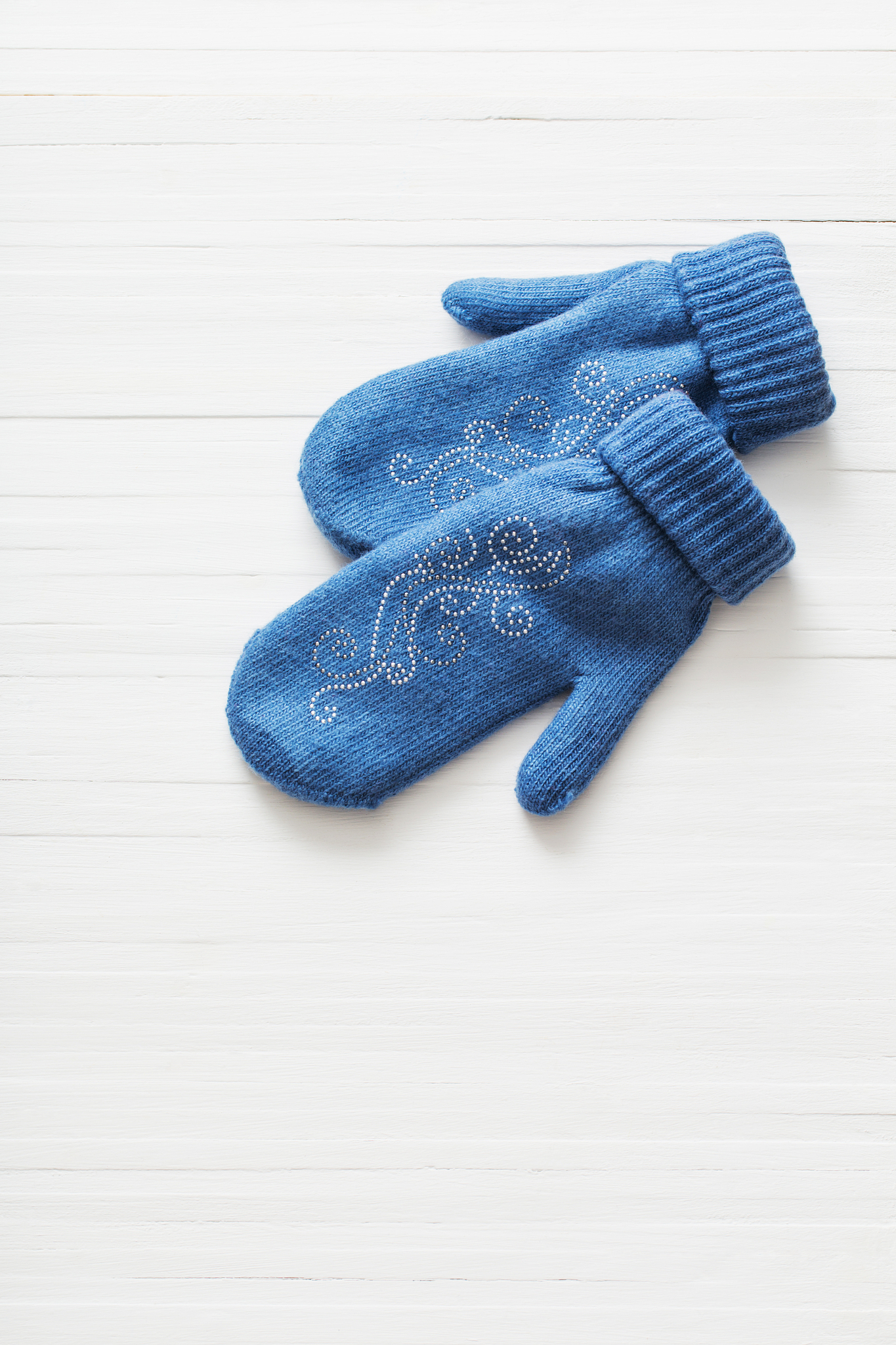 blue mittens on white wooden background