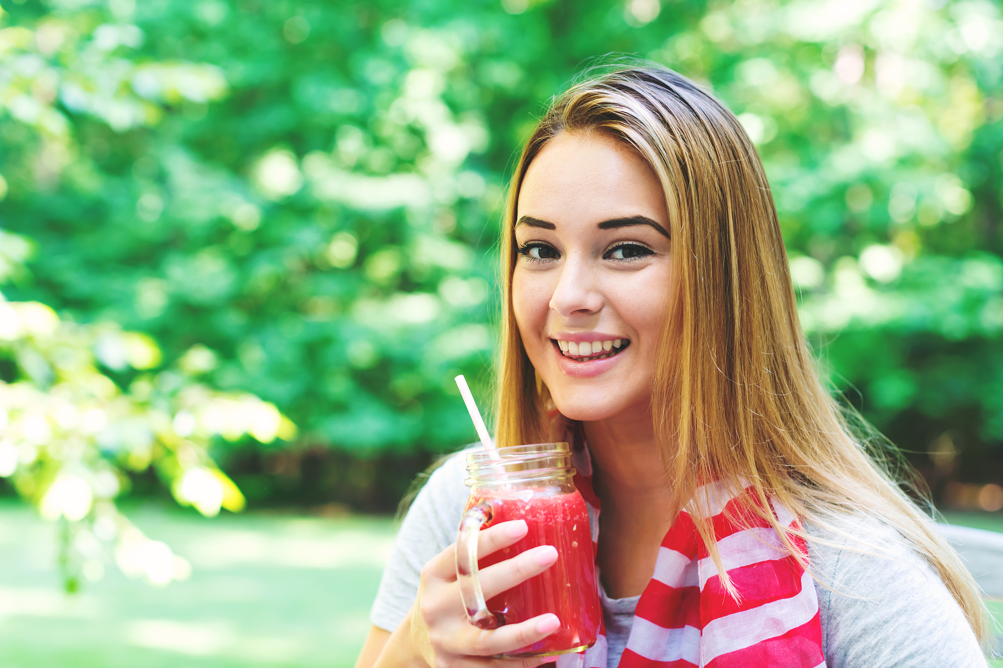 happy woman drinking a smoothie outside