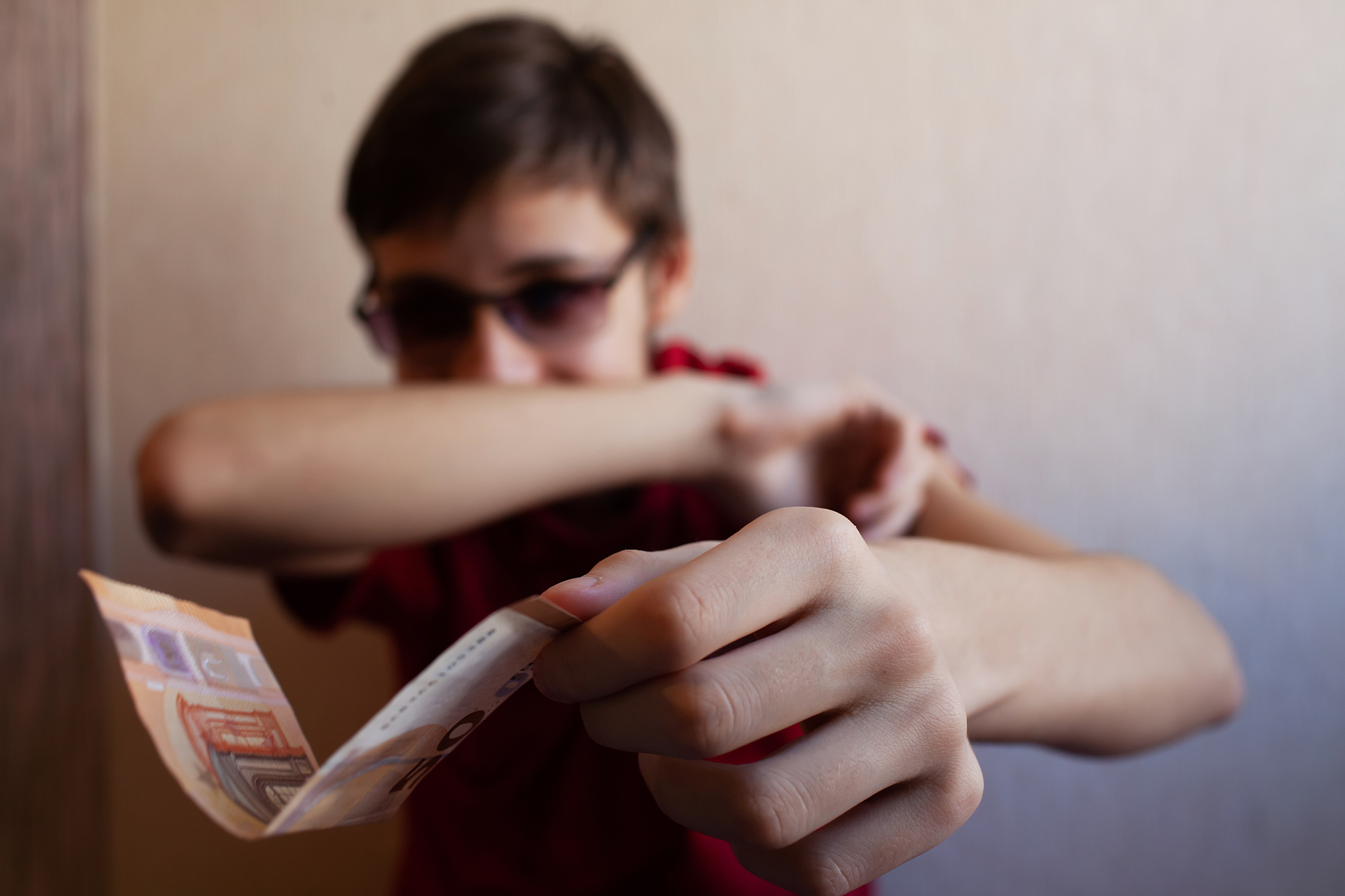 teen guy holds out his hand with a 50 euro bill