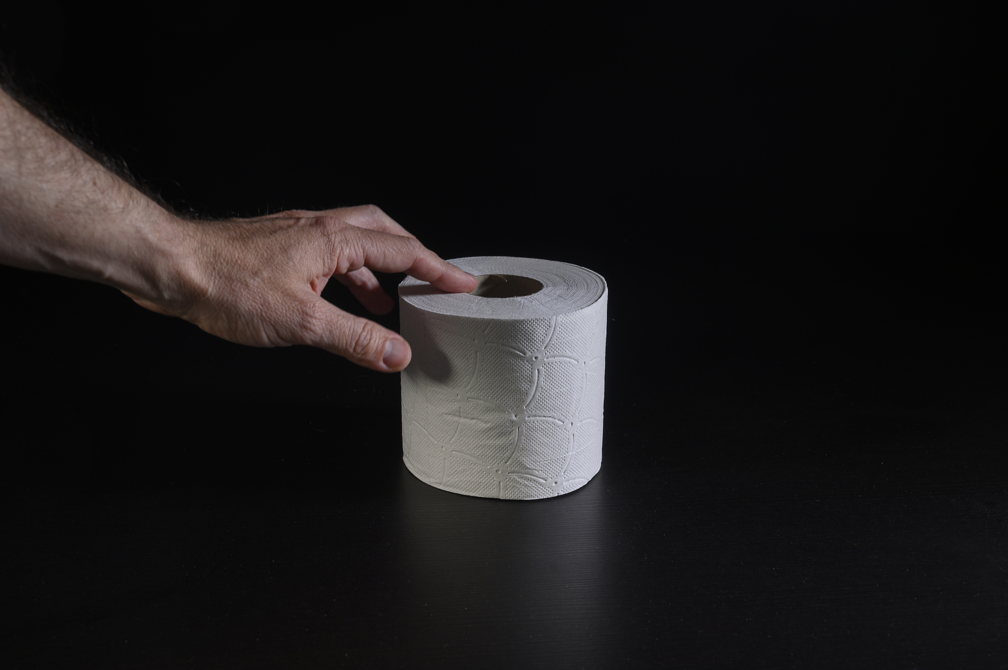 man's hand taking a roll of hygienic paper.