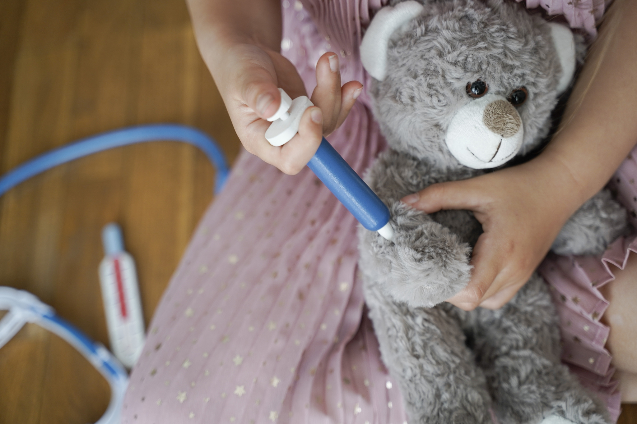 little girl playing doctors with her teddy bear
