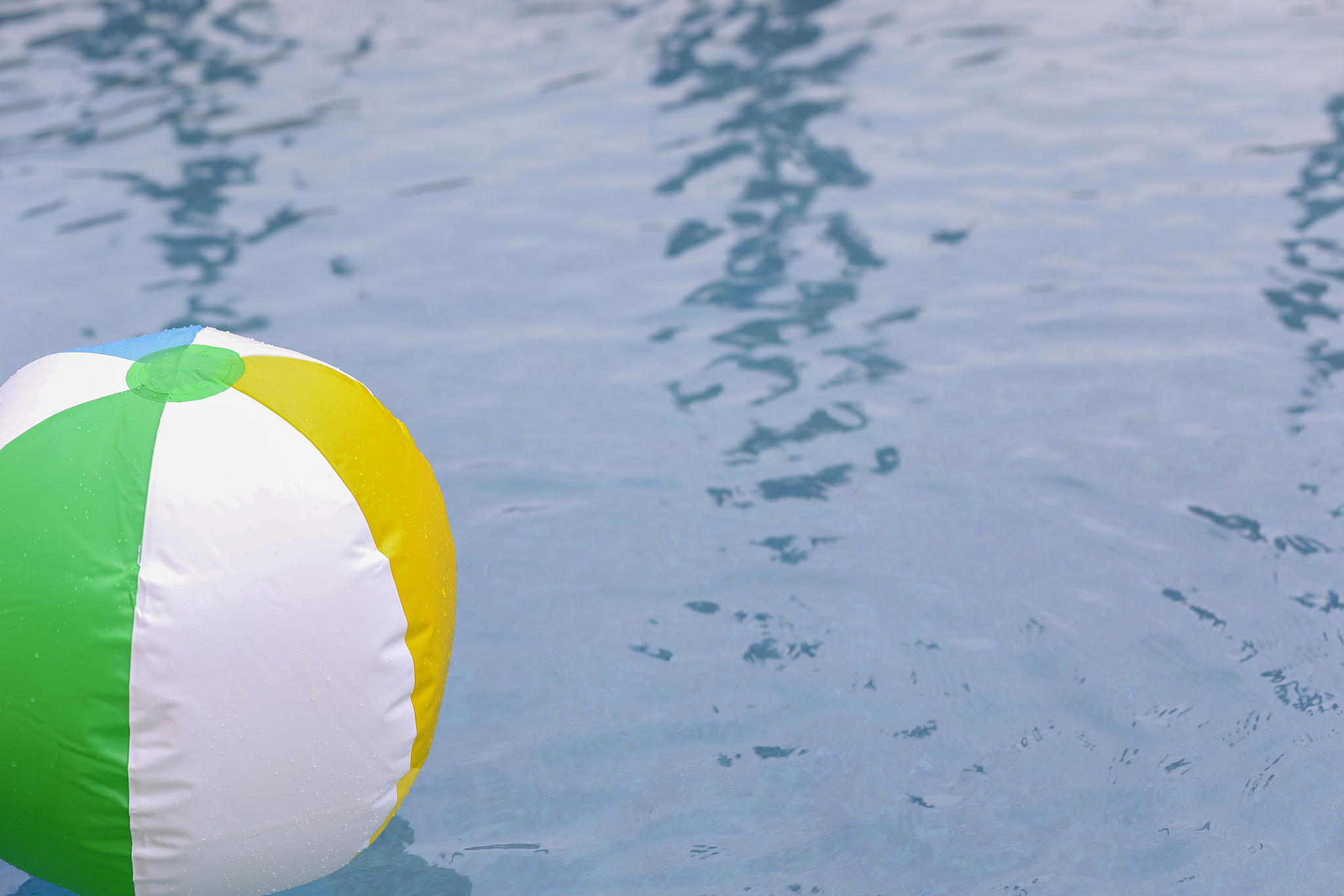 beach ball floating in refreshing swimming pool water.