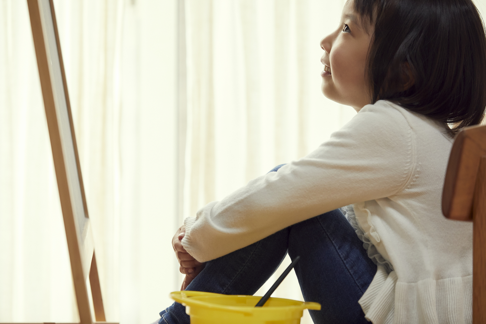 girl sitting in front of easel in living room