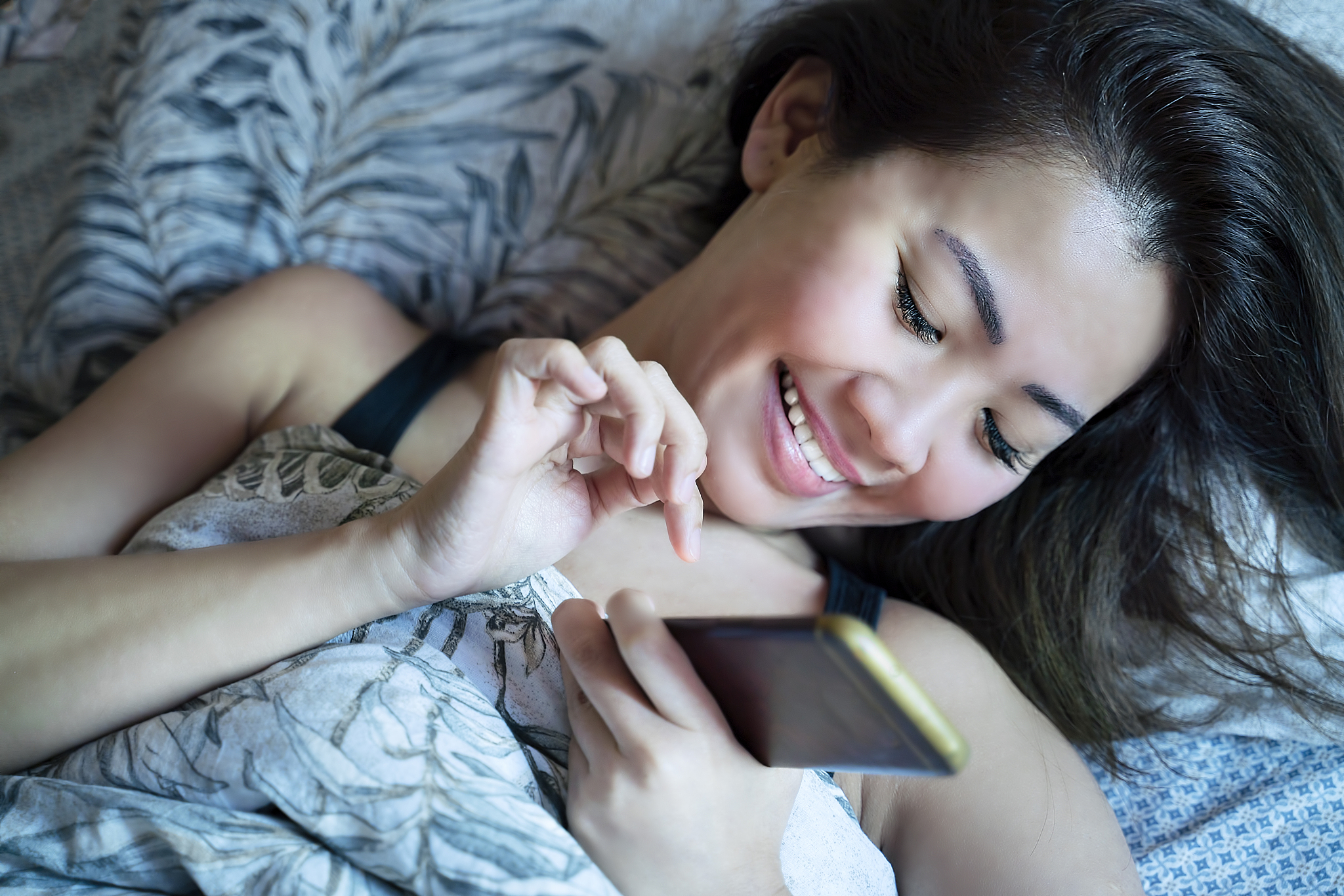 woman waking up in the morning and using mobile phone in bed