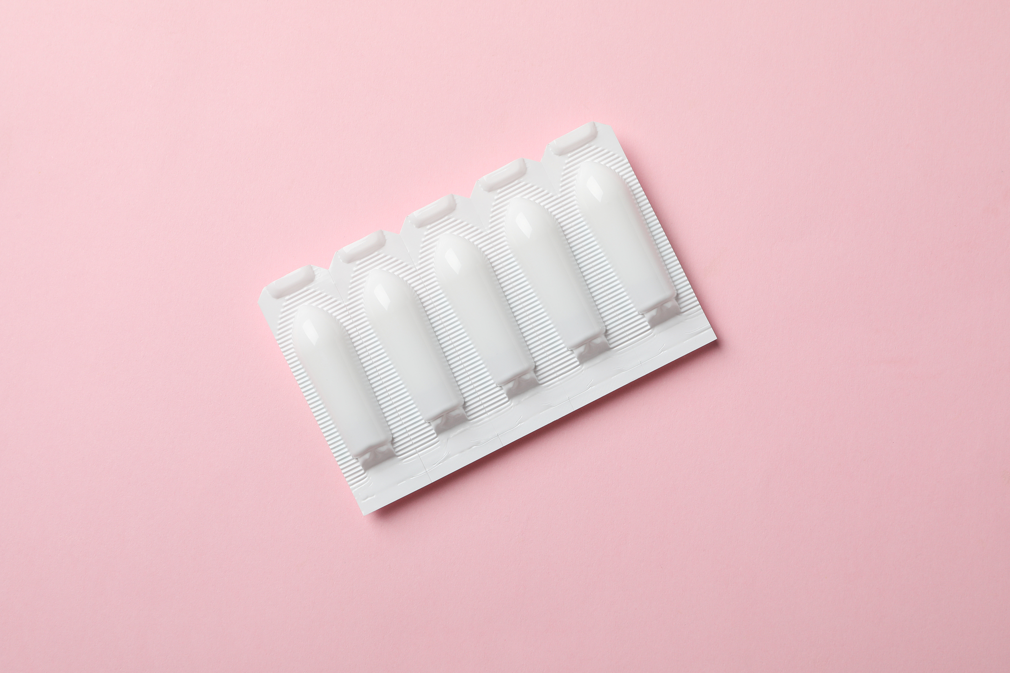 anal or vaginal candles on pink background, top view