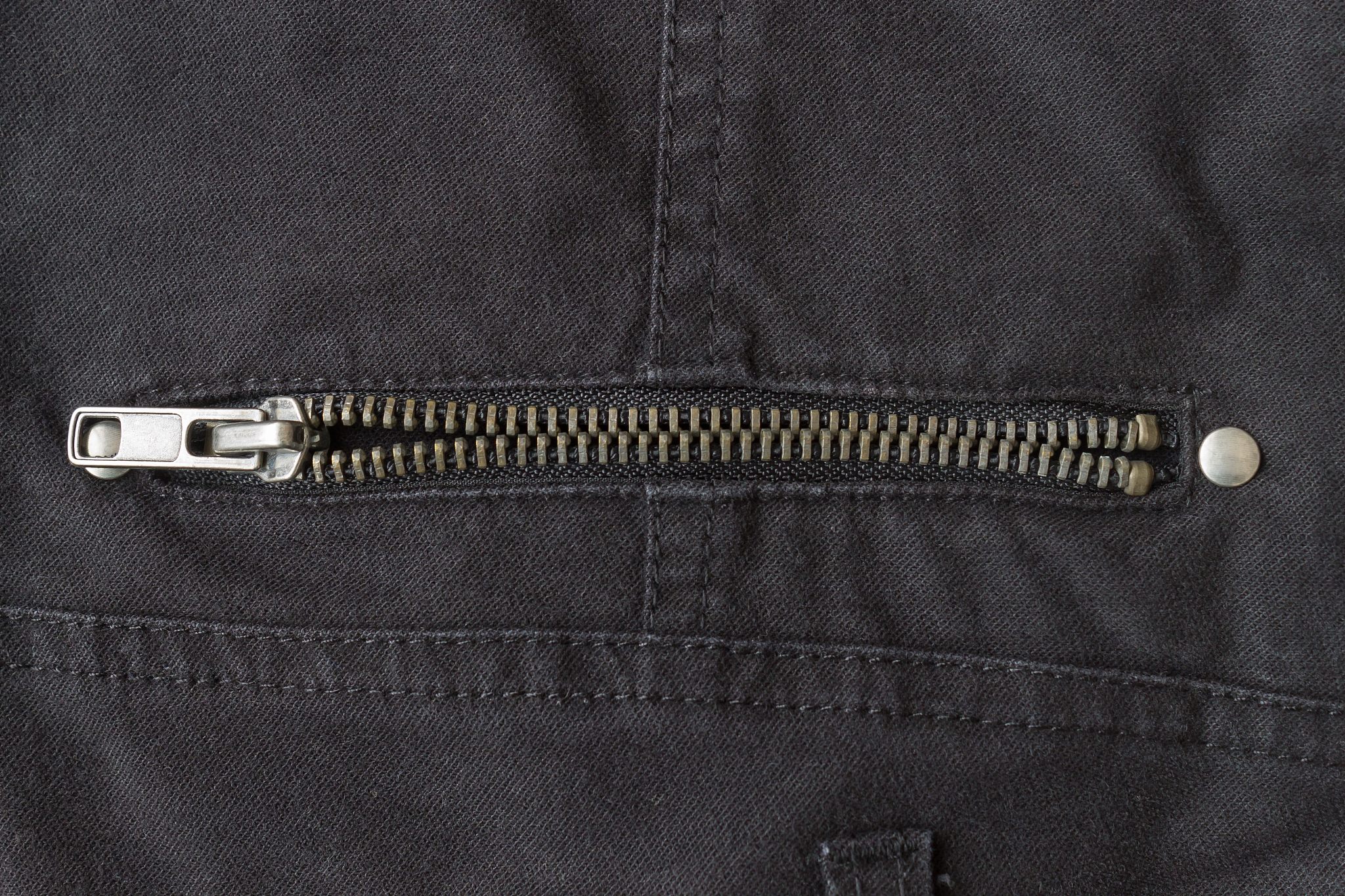 open brass zip on black jeans texture background