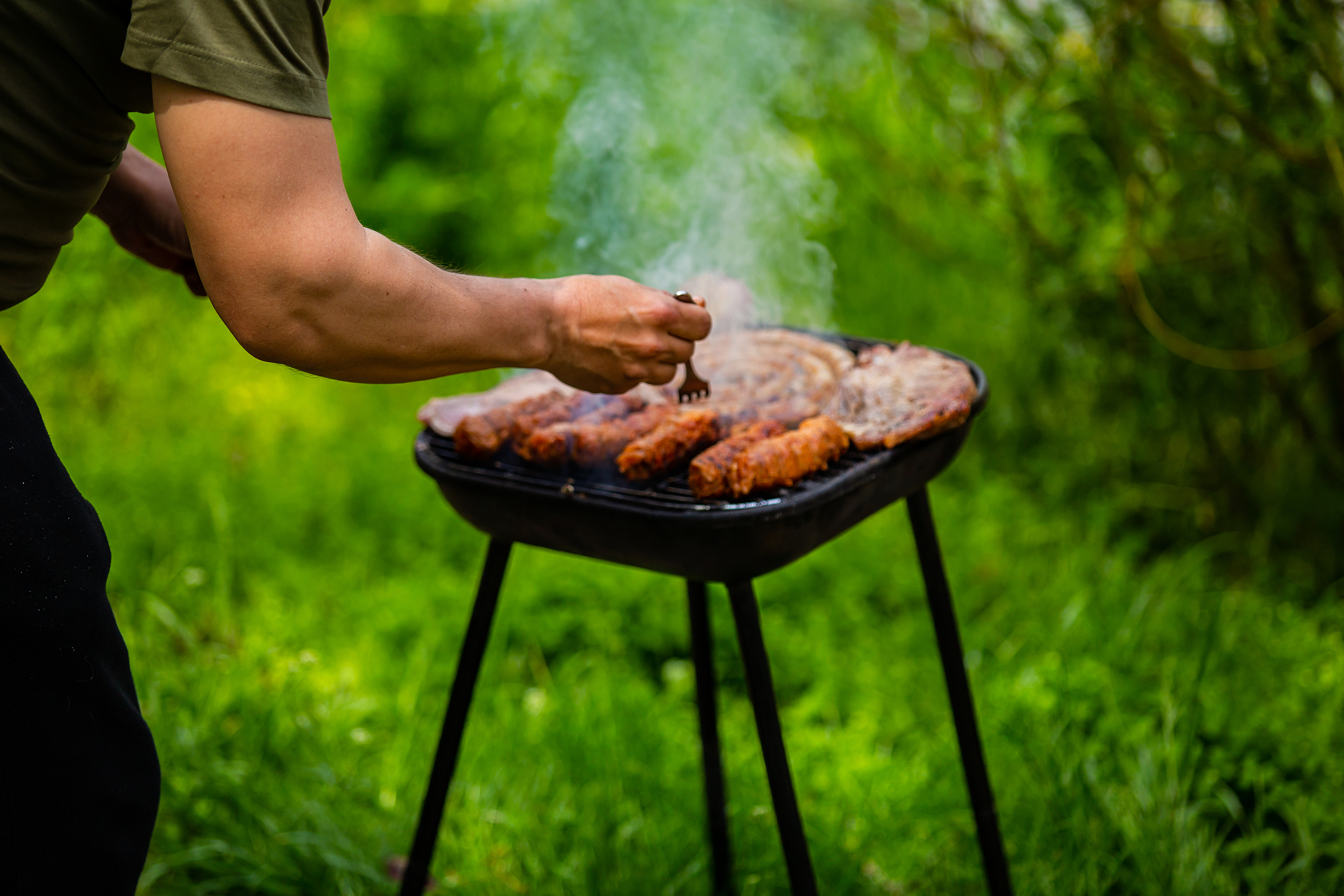 close up of hand with fork checking and turning meat products on